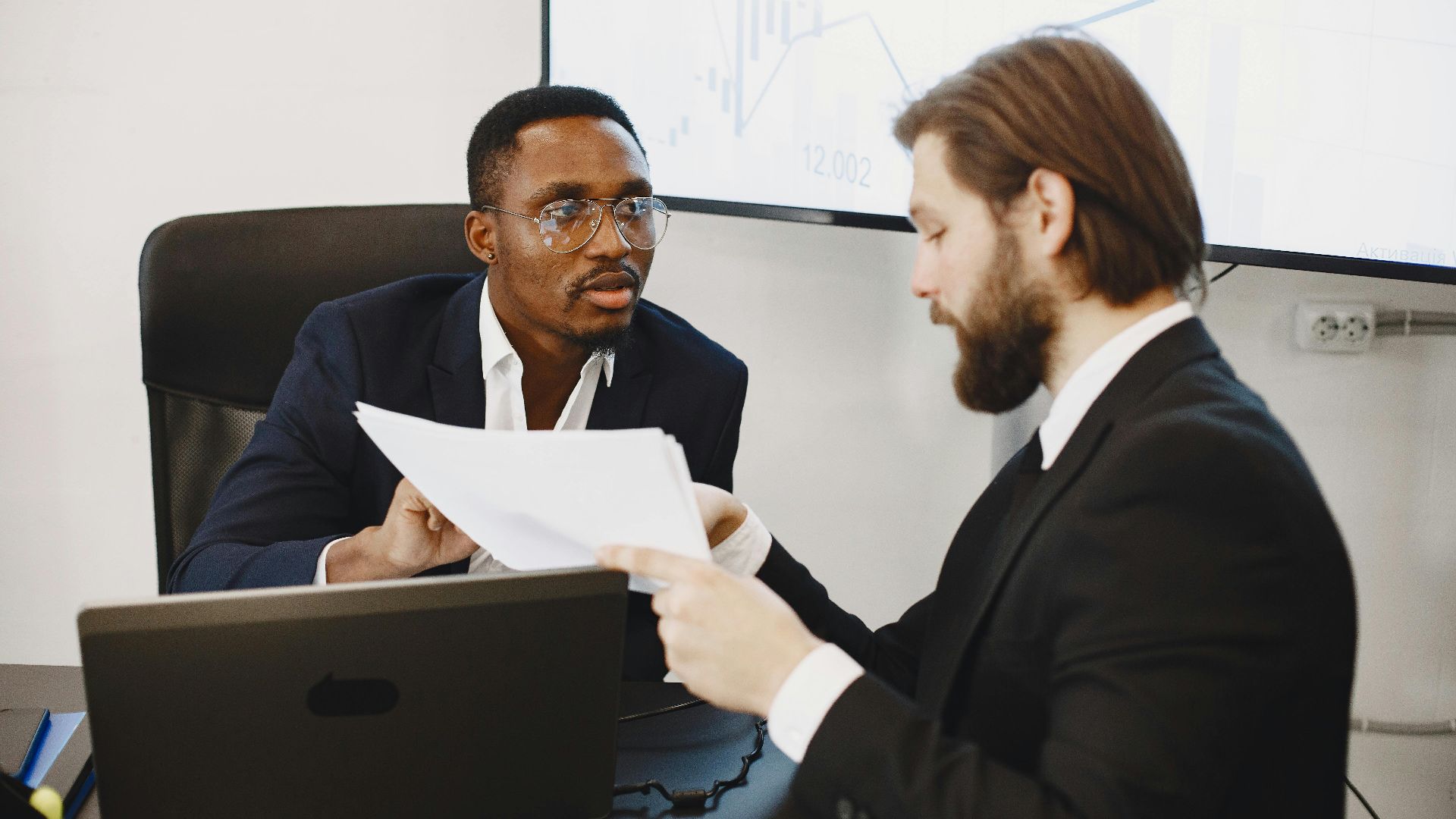 Professionals examining documents in an office business meeting setup.