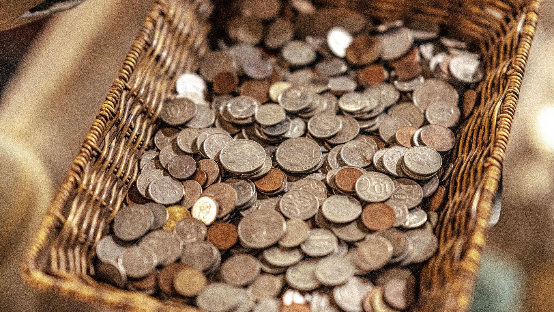 A wicker basket filled with various coins, symbolizing wealth and economic activity.