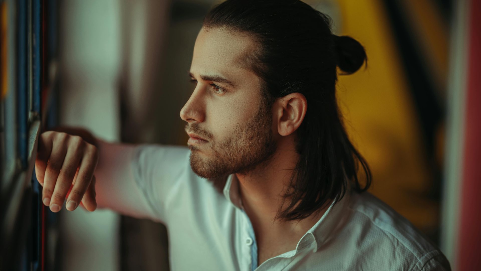 Portrait of a man gazing out a window in Piranshahr, Iran, soft natural light enhancing mood.