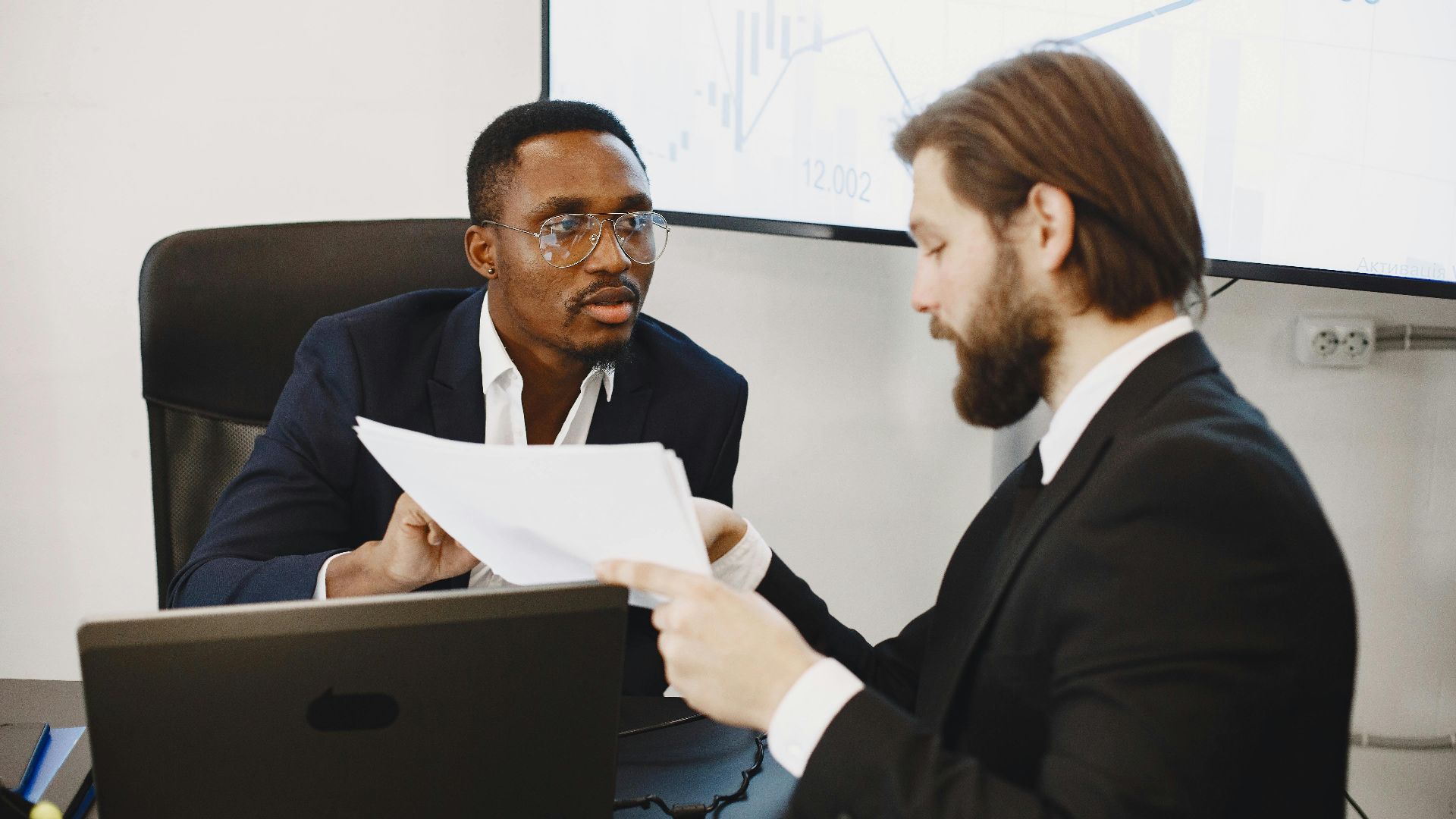 Professionals examining documents in an office business meeting setup.
