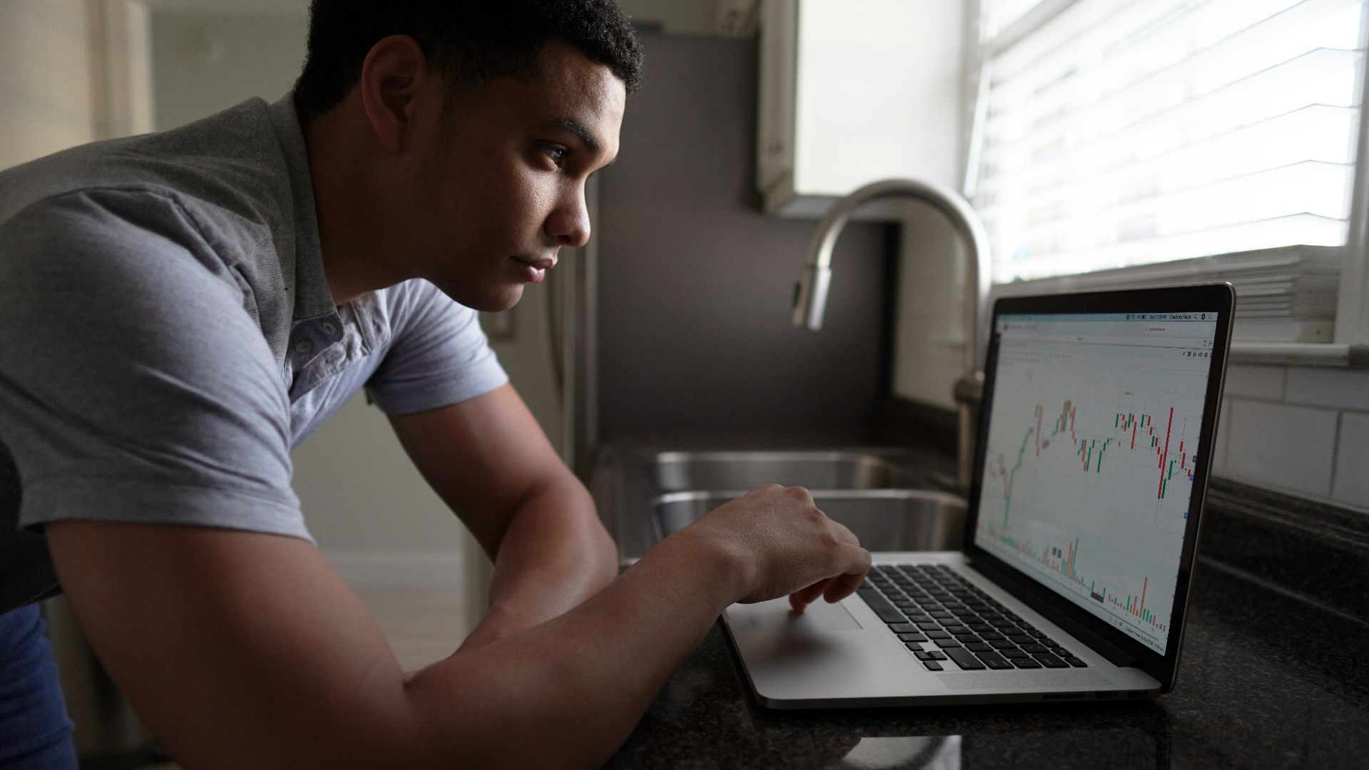 man in gray t-shirt using macbook pro