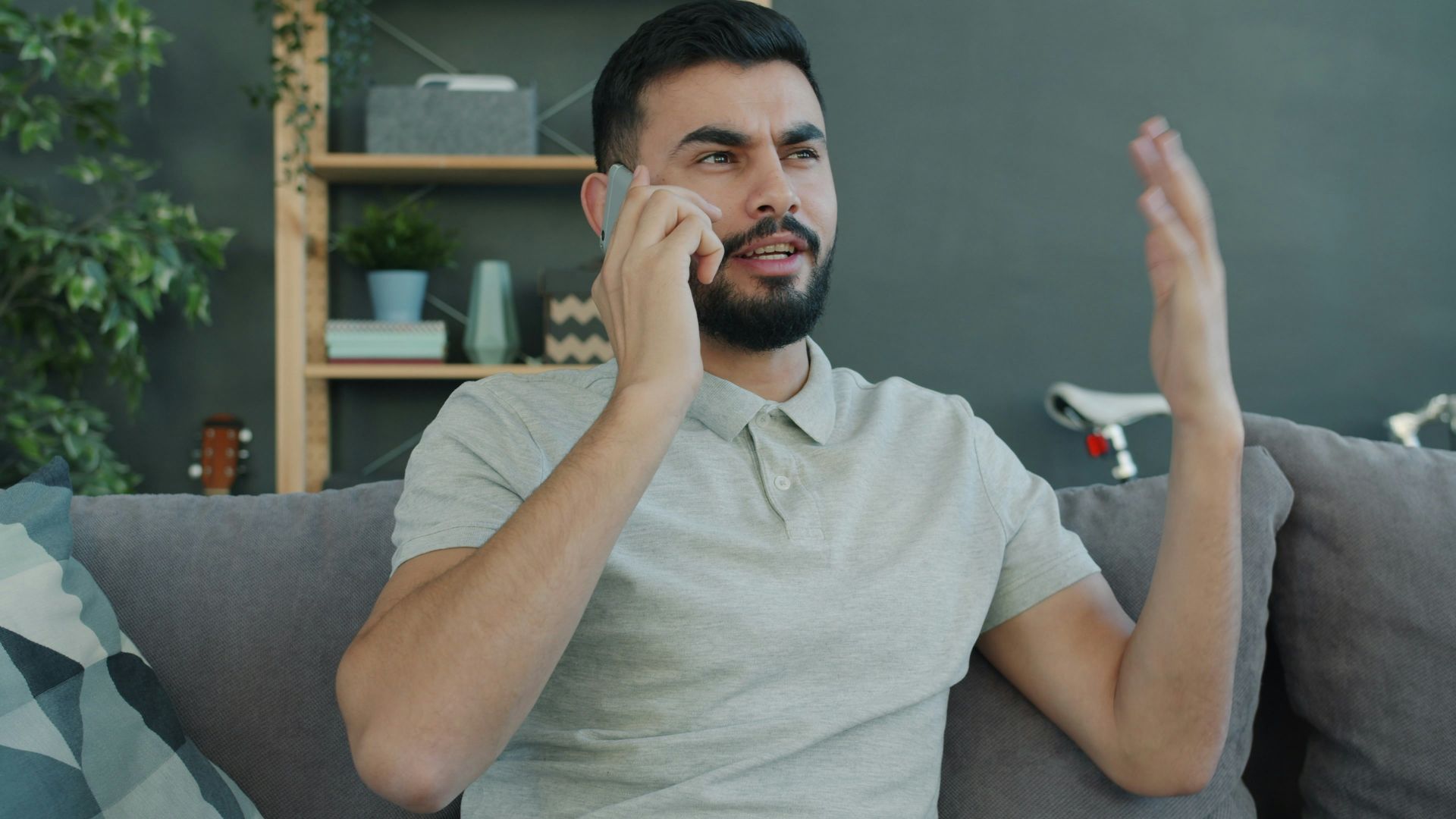 Man talking animatedly on the phone while sitting on couch.