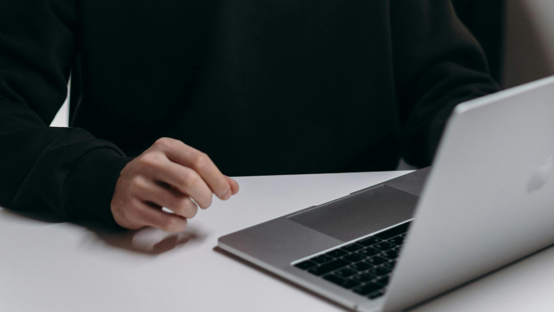 A focused young man using a laptop at a desk in a stylish home office setting.