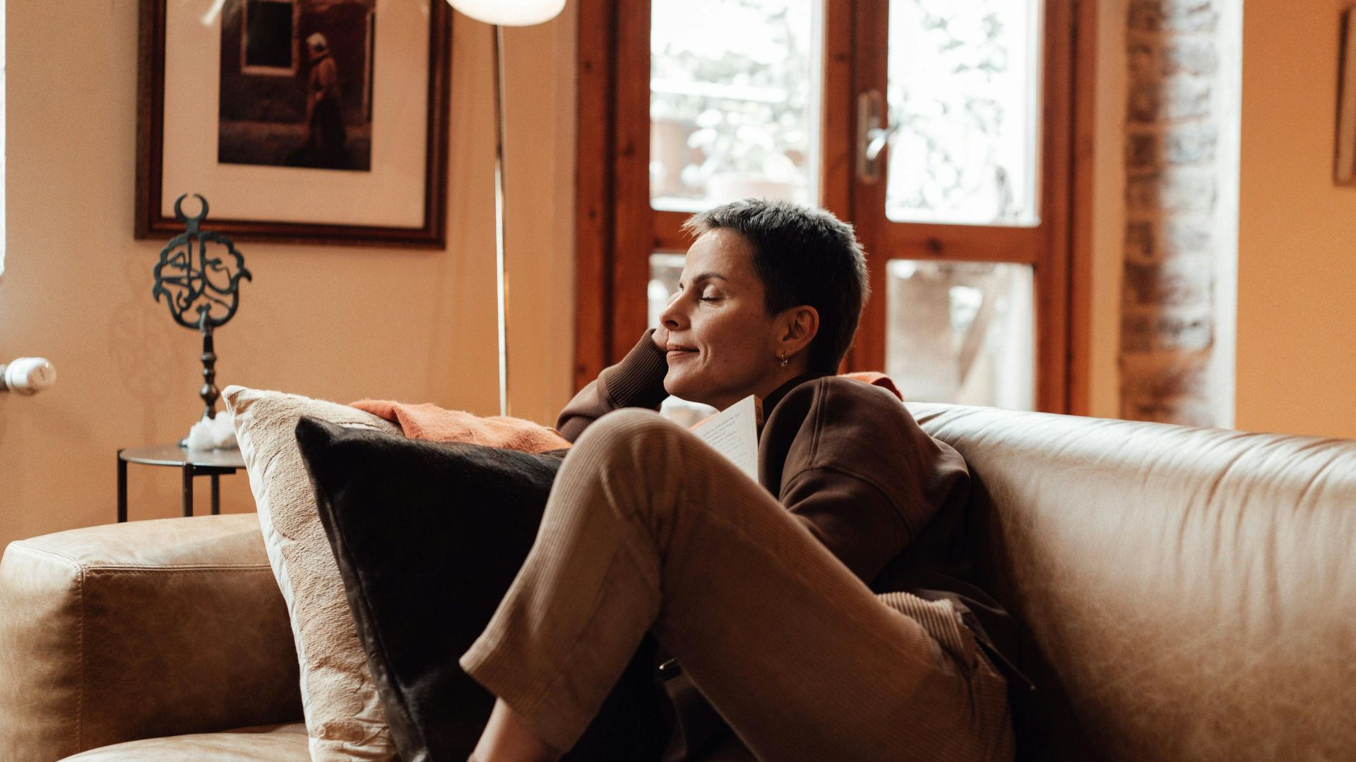 A woman relaxing on a leather couch in a cozy living room, reading peacefully.