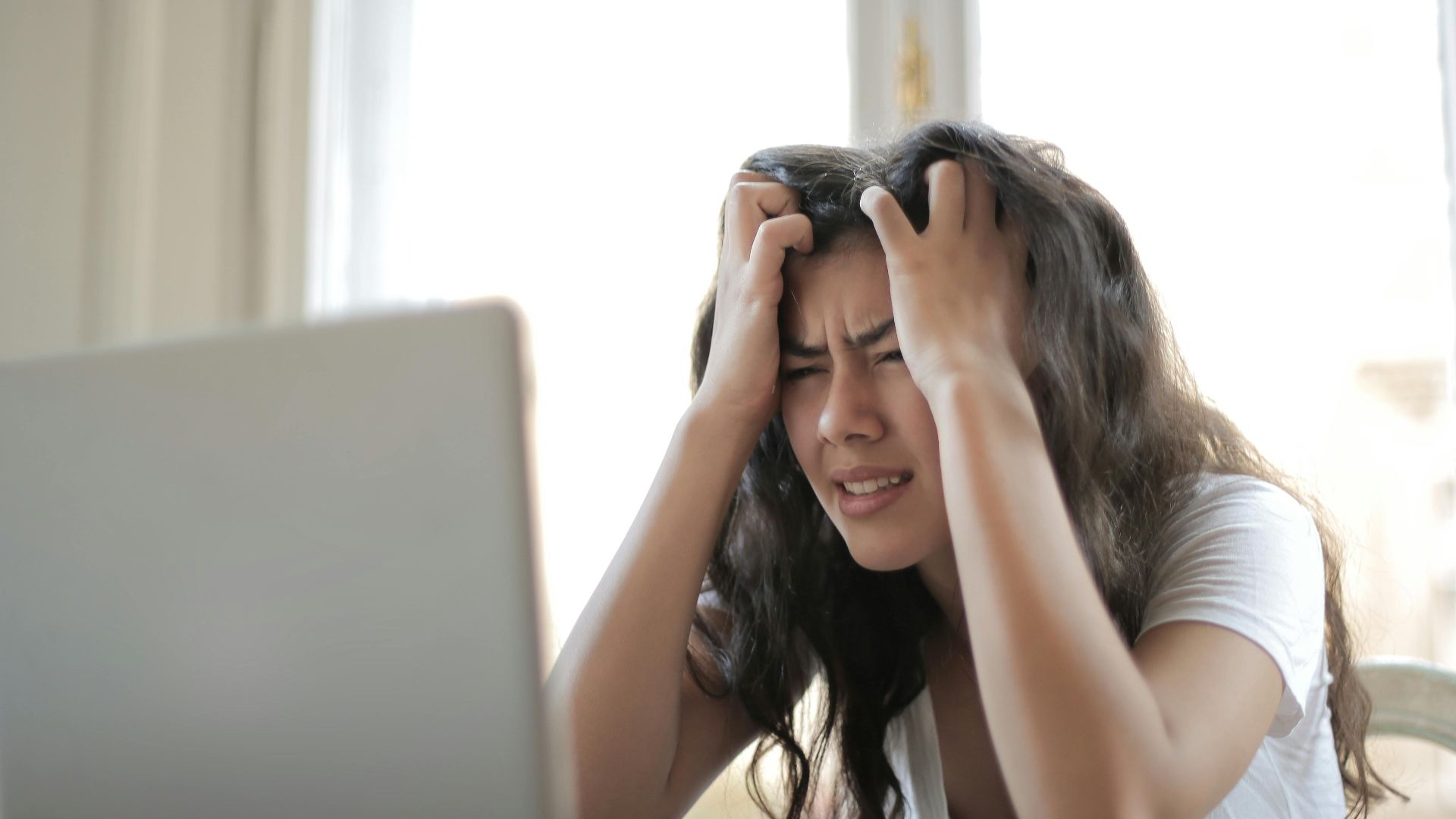 Frustrated woman struggling with remote work stress and digital challenges indoors.