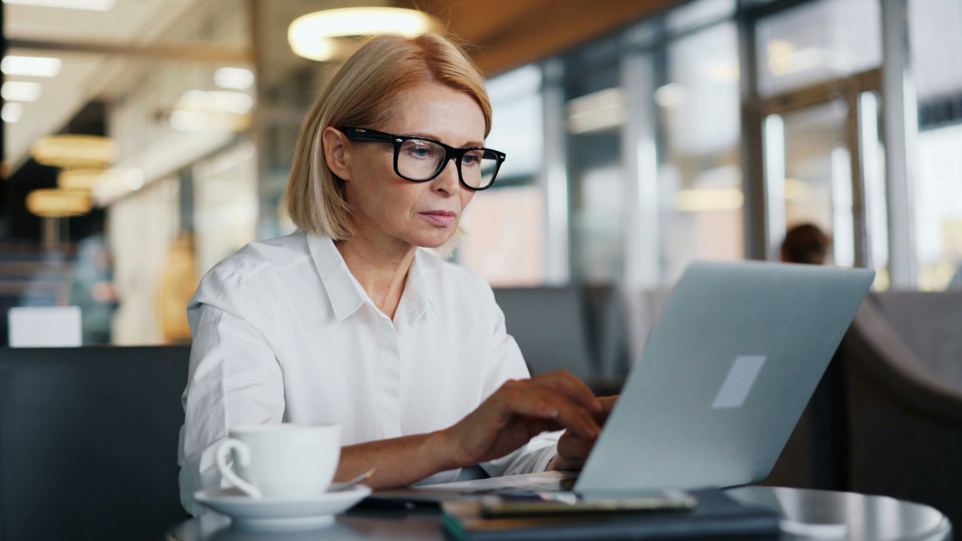 a woman sitting at a table using a laptop computer