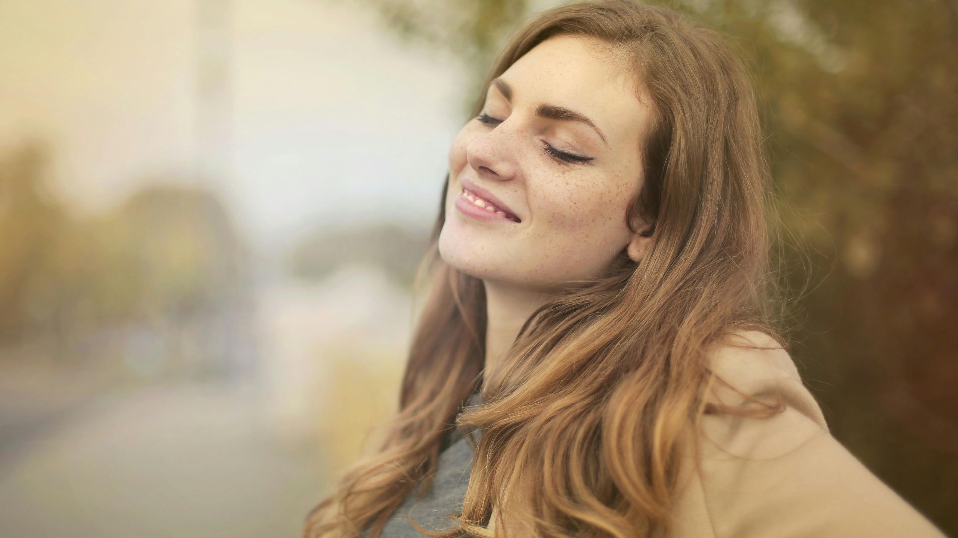 Portrait of a woman with closed eyes, enjoying the outdoors in autumn. Bright and serene.