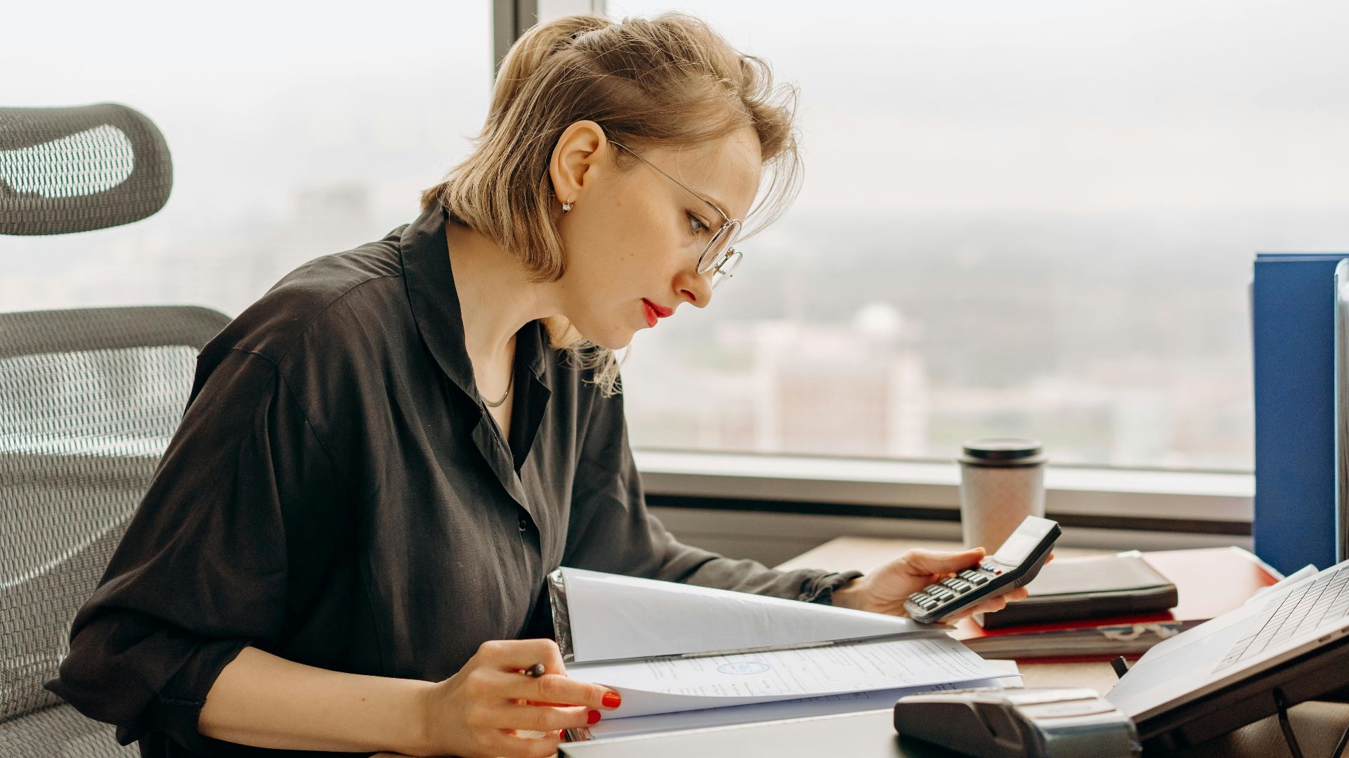 Woman accountant calculating financial documents at office desk.
