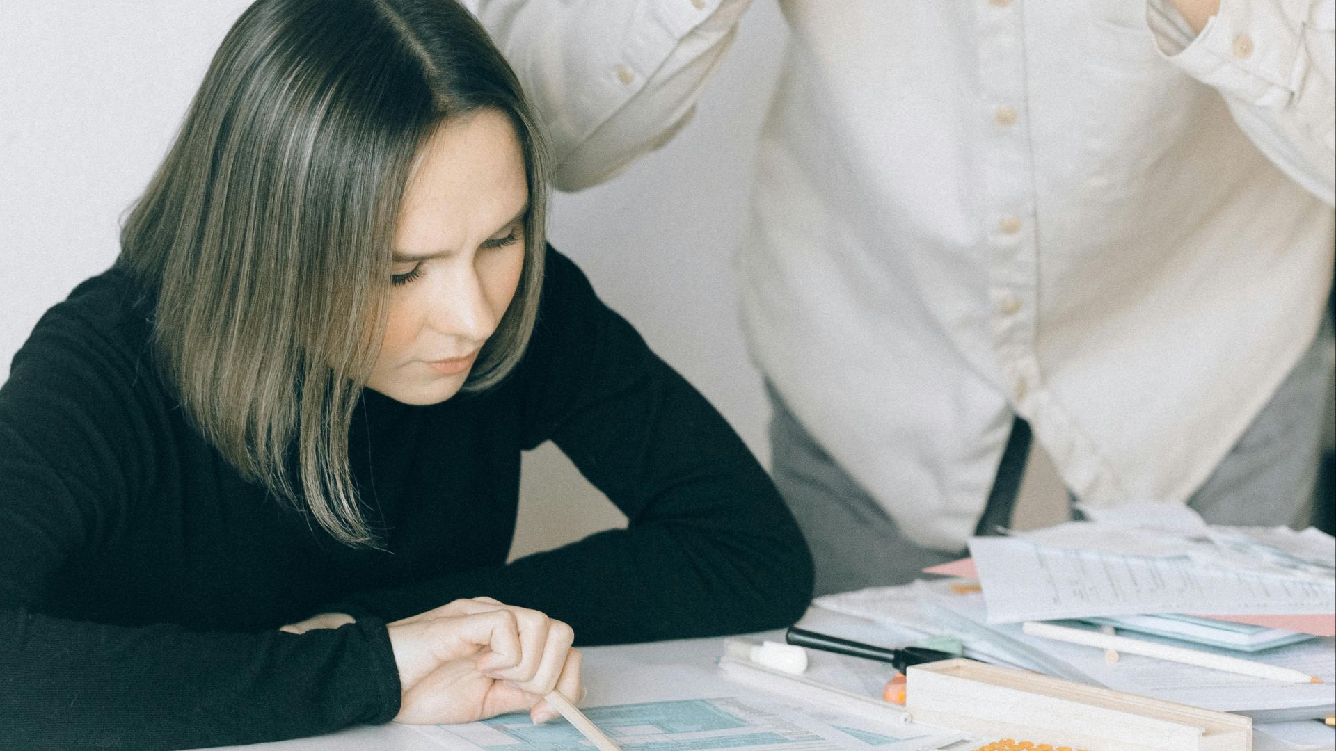Young couple in discussion over financial papers, looking stressed at a table indoors.