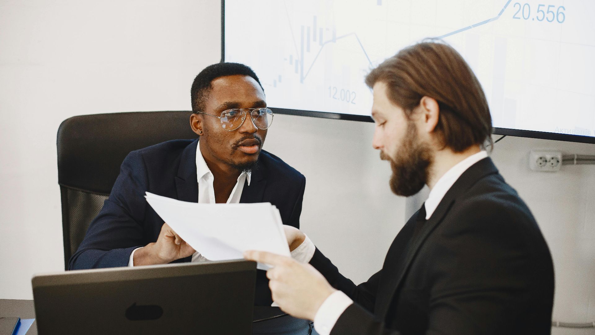 Professionals examining documents in an office business meeting setup.