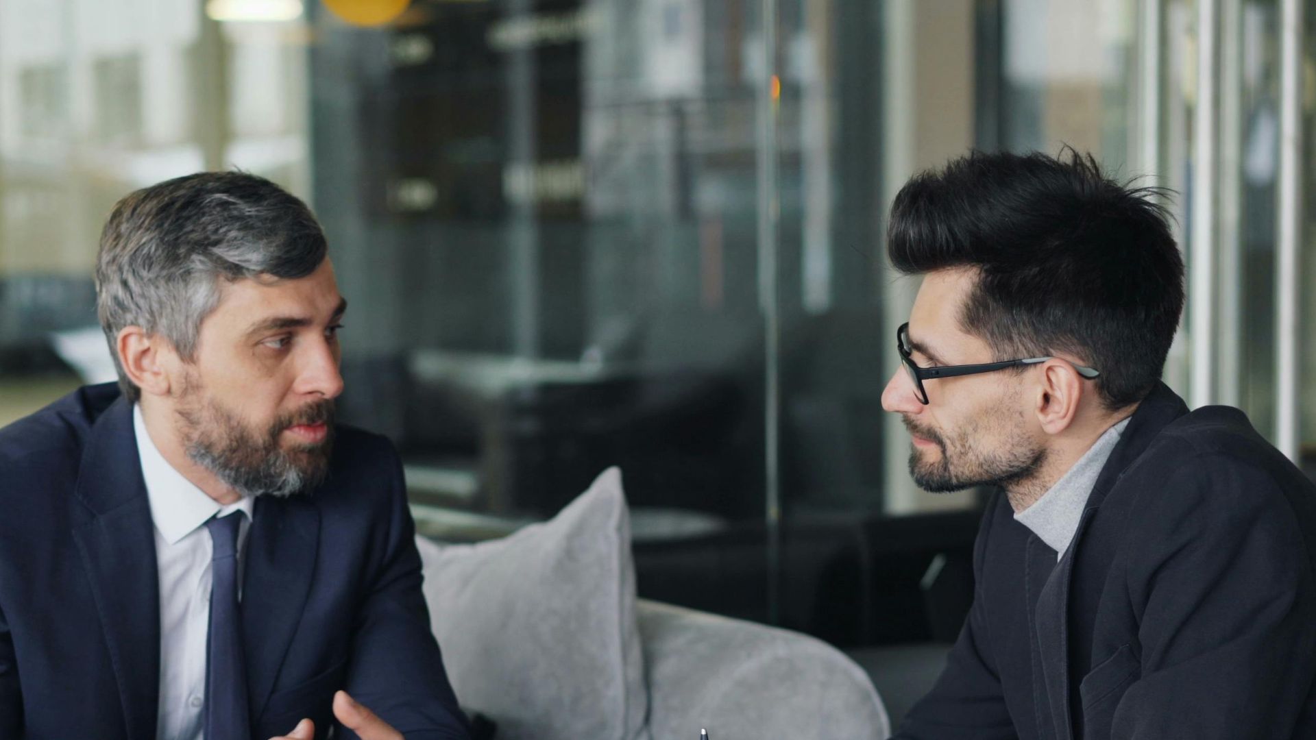 Two businessmen having a meeting with laptops, papers, and coffee at a modern office.
