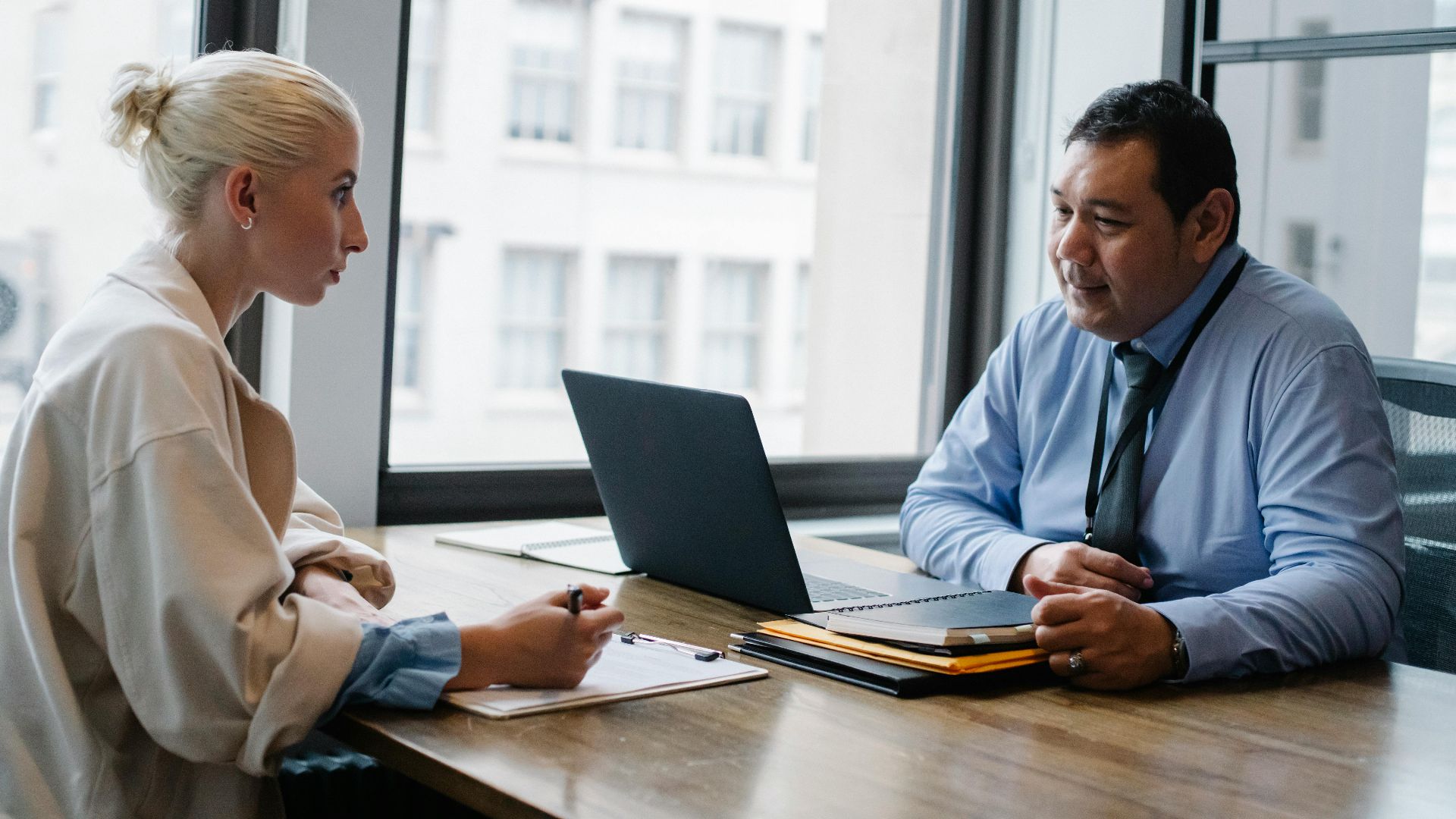 Ethnic boss asking question to female candidate filling information form on clipboard during hiring meeting