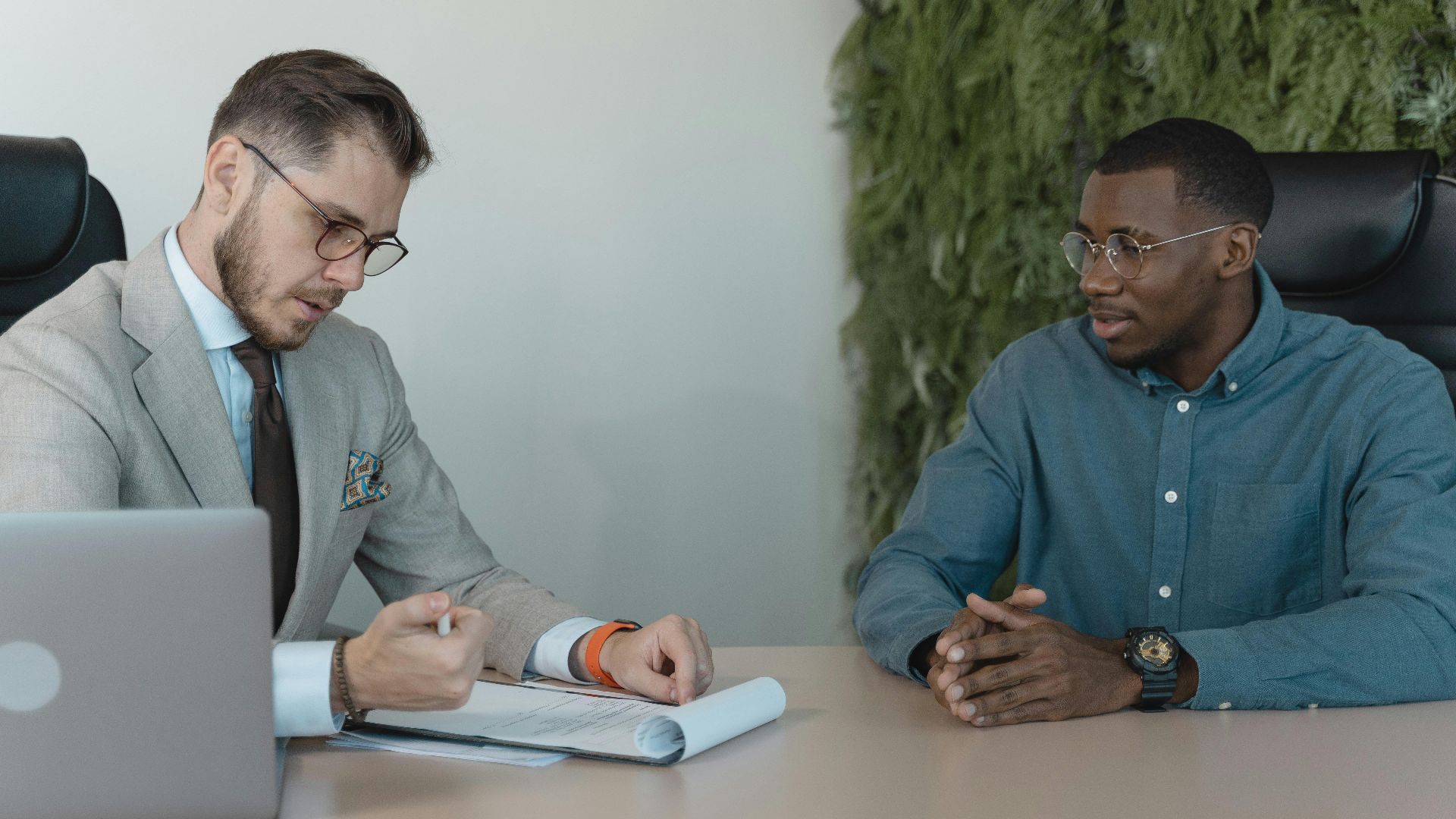 A professional job interview between two men in a modern office environment.