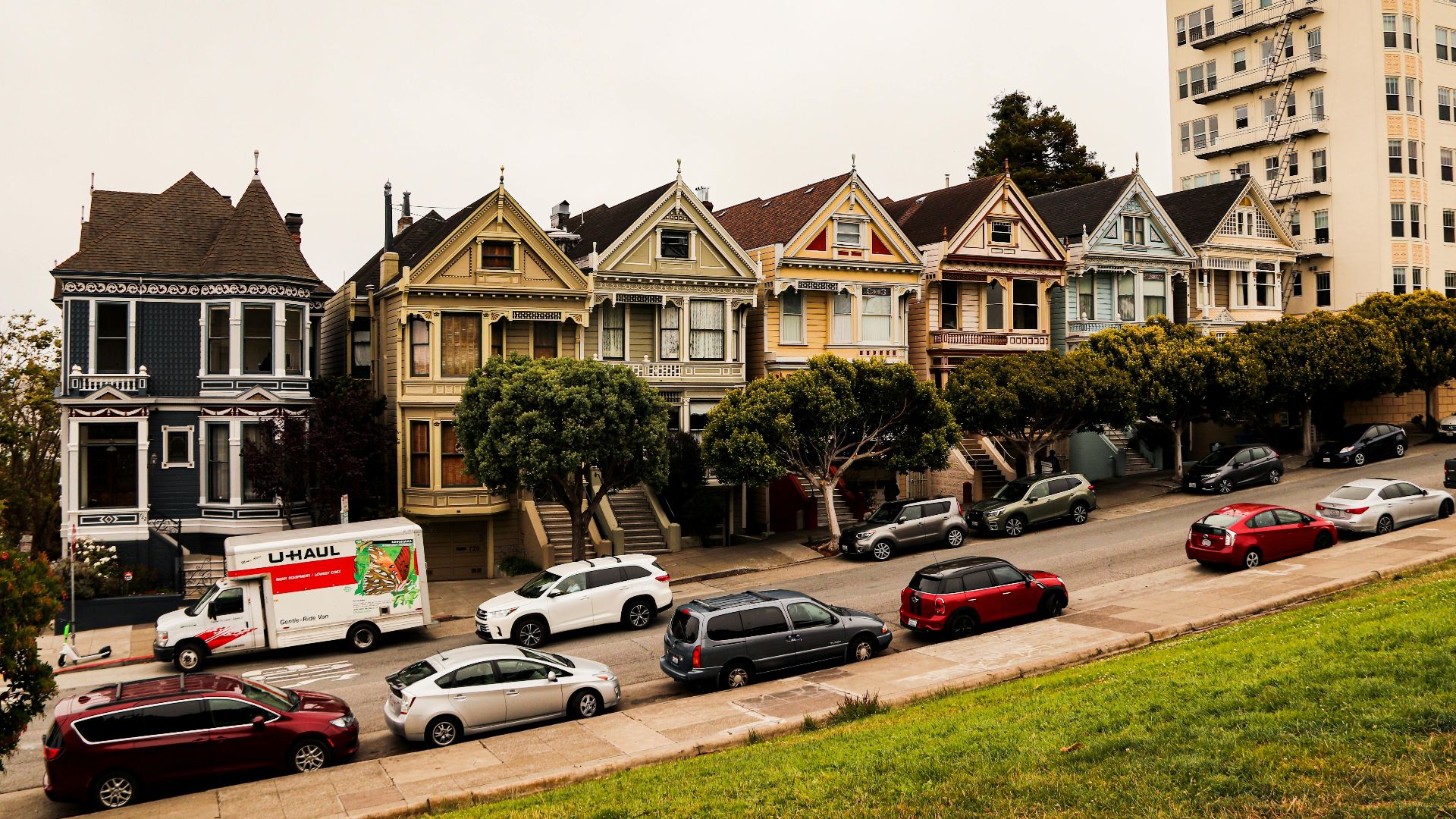 Historic Painted Ladies homes with parked cars in San Francisco, showcasing Victorian architecture.