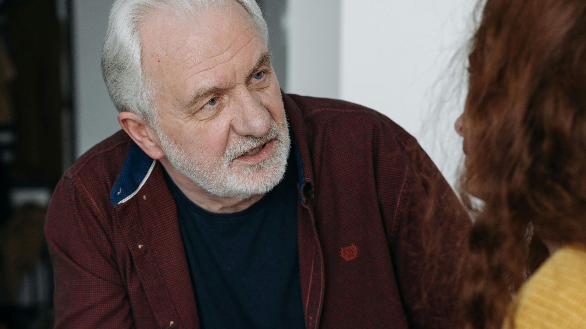 An elderly man and young woman discussing something important indoors.