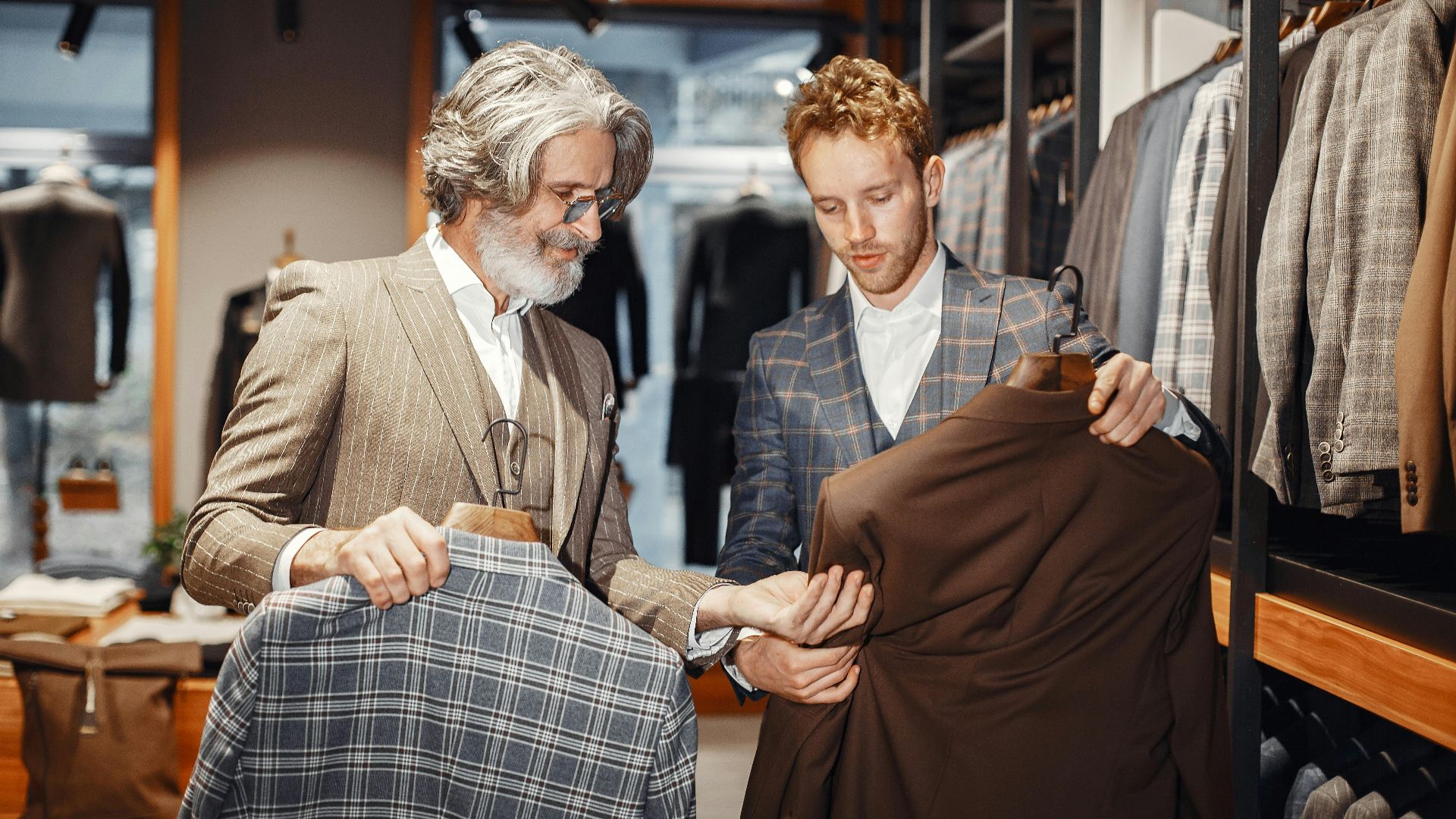 Two men selecting suits in a modern fashion boutique, highlighting style and elegance.