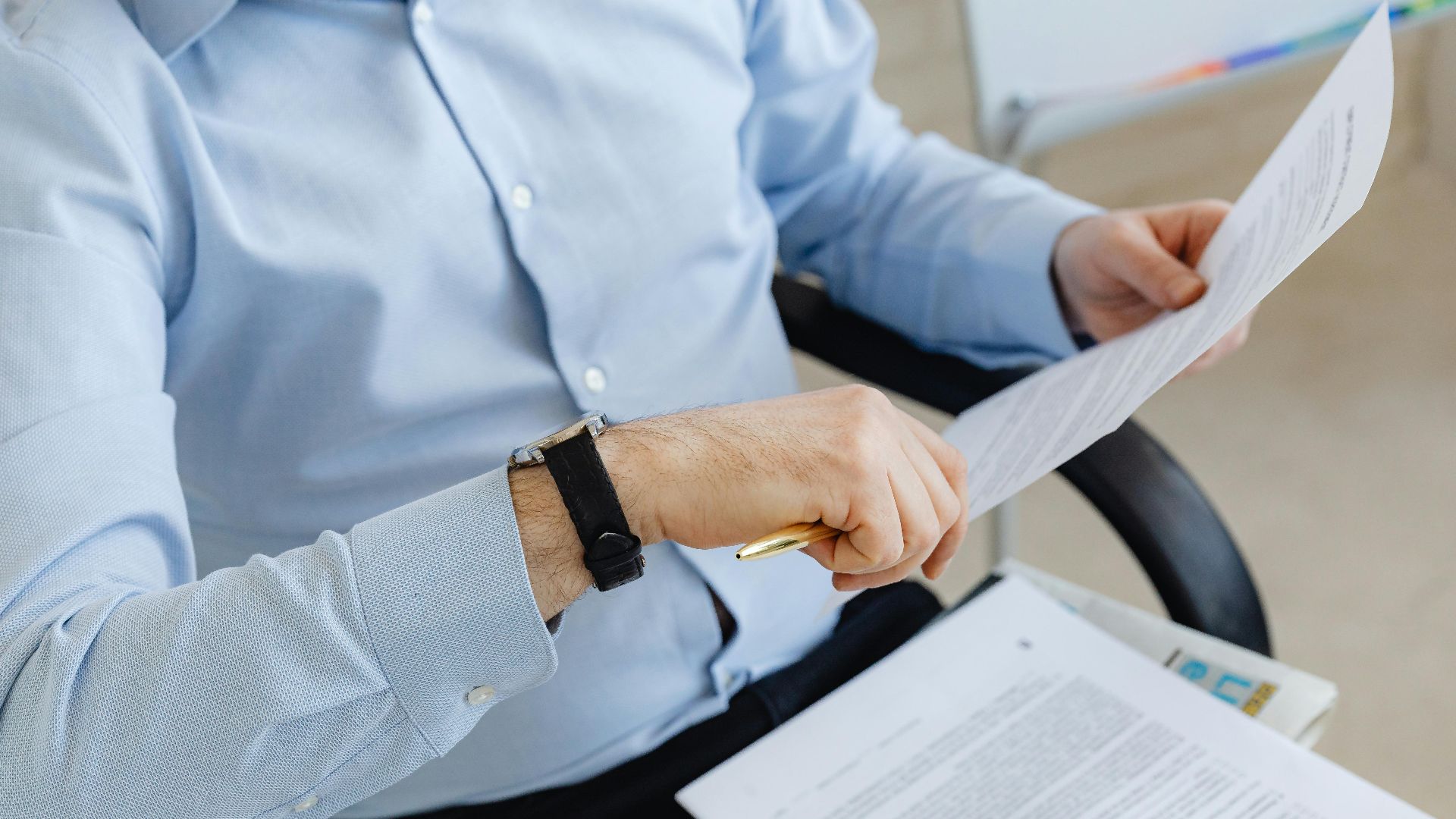 Businessman reviewing papers in office setting, highlighting analysis and attention to detail.
