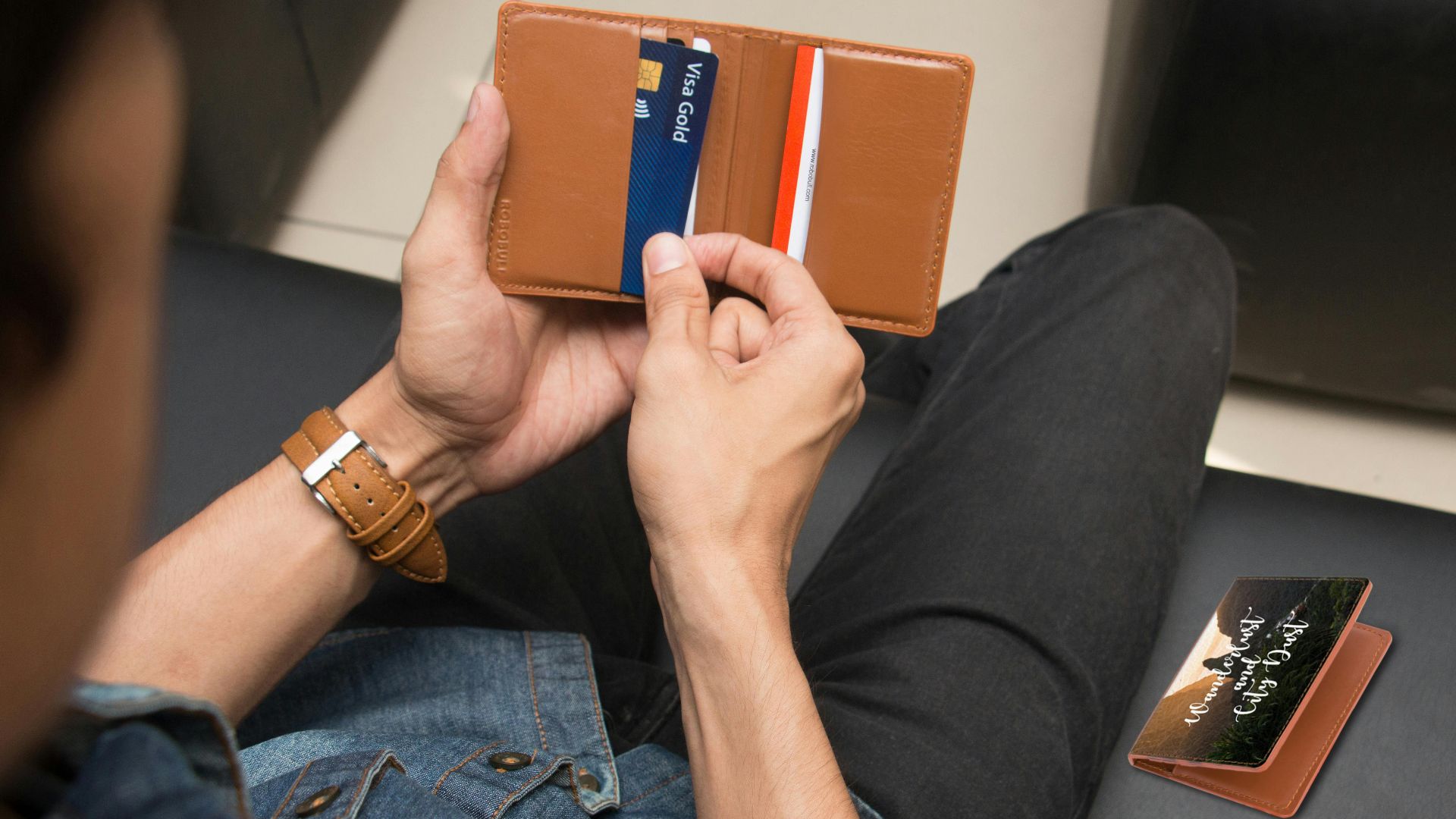 Over-the-shoulder view of a person holding a leather wallet displaying credit cards.