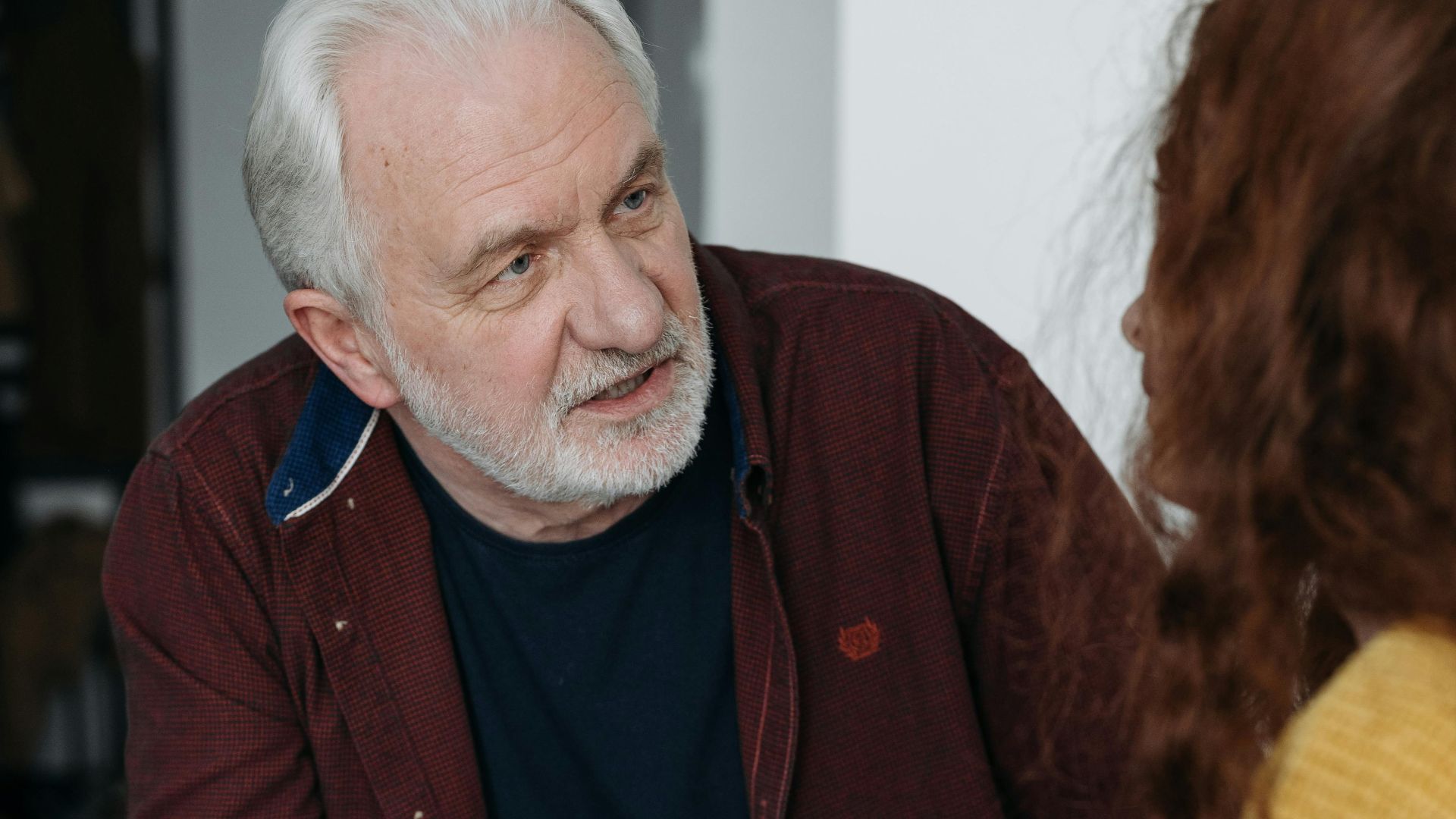 An elderly man and young woman discussing something important indoors.