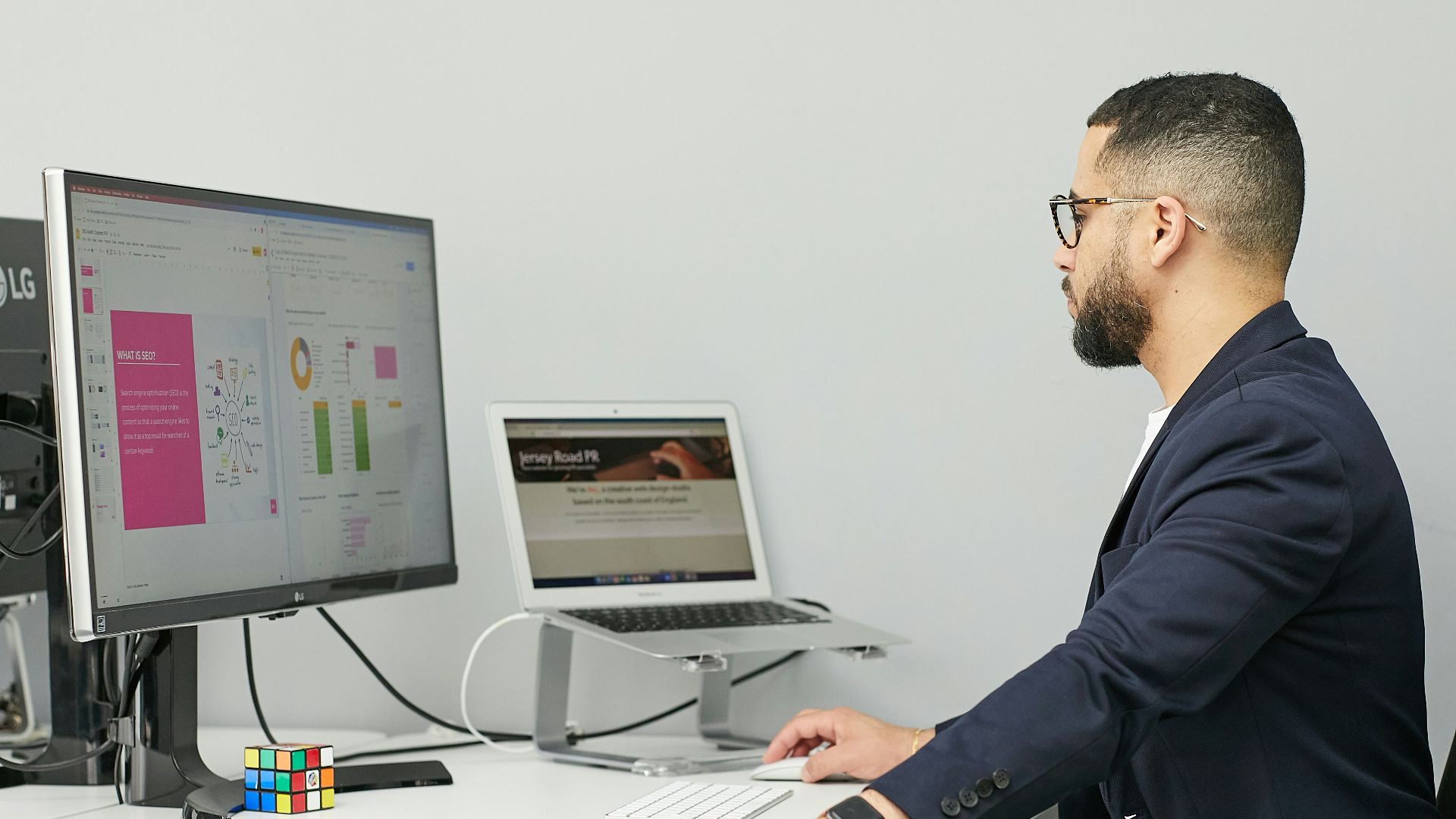 a man sitting at a desk with a laptop and a computer