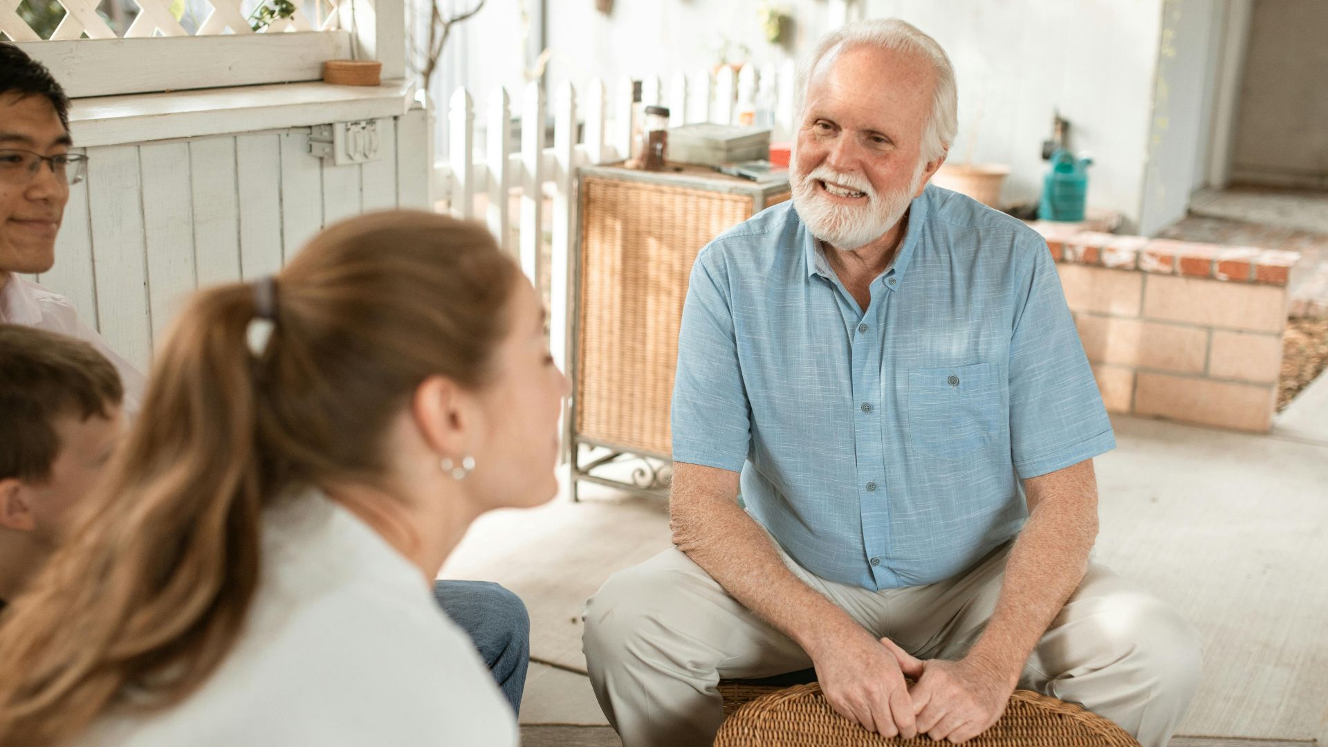 Elderly man enjoying a pleasant family gathering outdoors with diverse group sitting together.