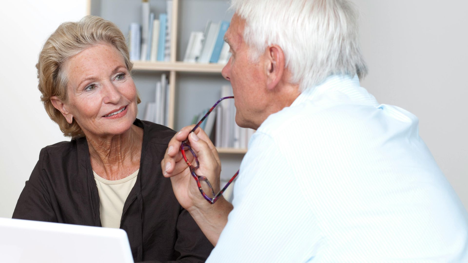 Elderly couple sharing a meaningful conversation indoors with affection and understanding.