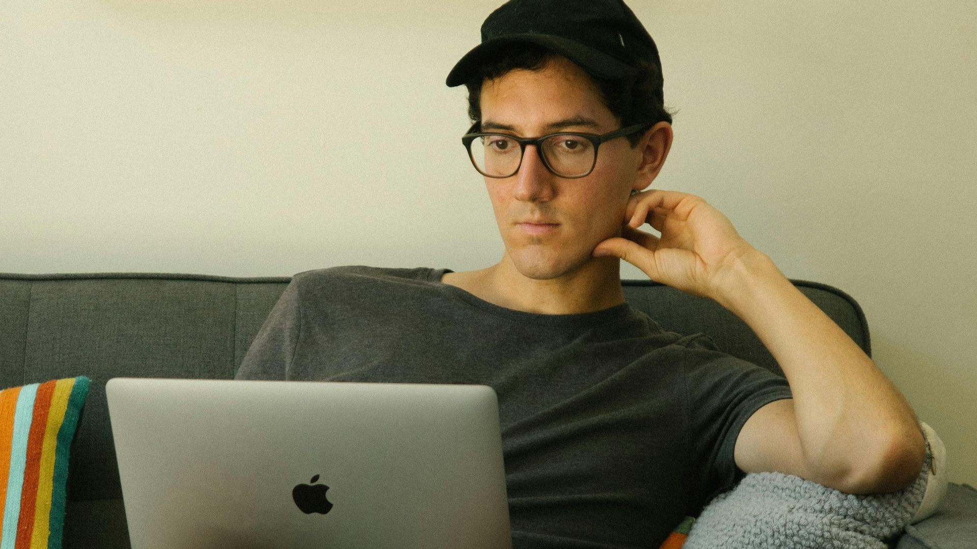Man sitting comfortably on a sofa using a laptop. Ideal for work-from-home themes.