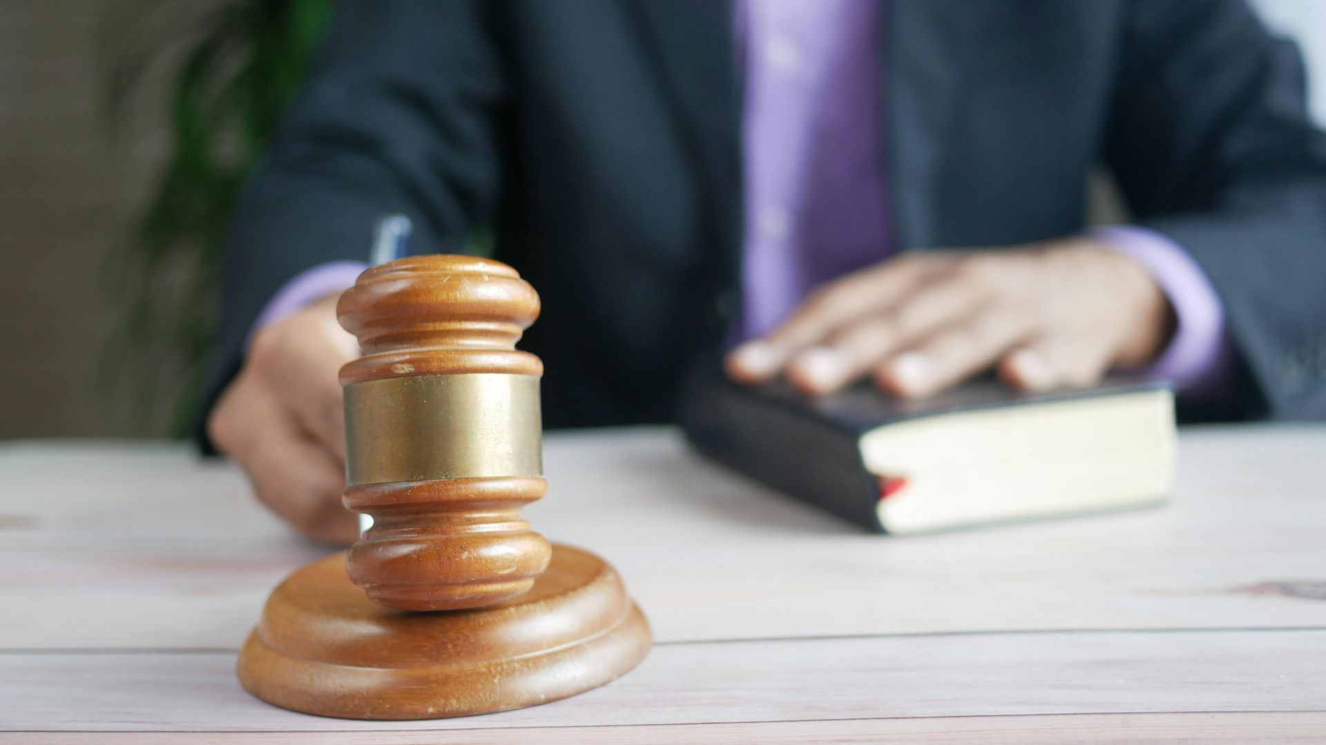 A wooden gavel and legal book represent justice in a court setting, emphasizing order and legal authority.