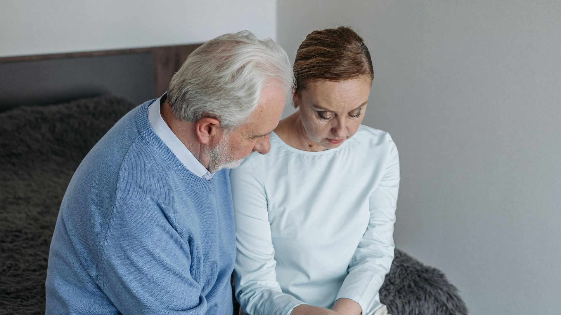 Elderly couple sitting together indoors, reflecting on an emotional moment.