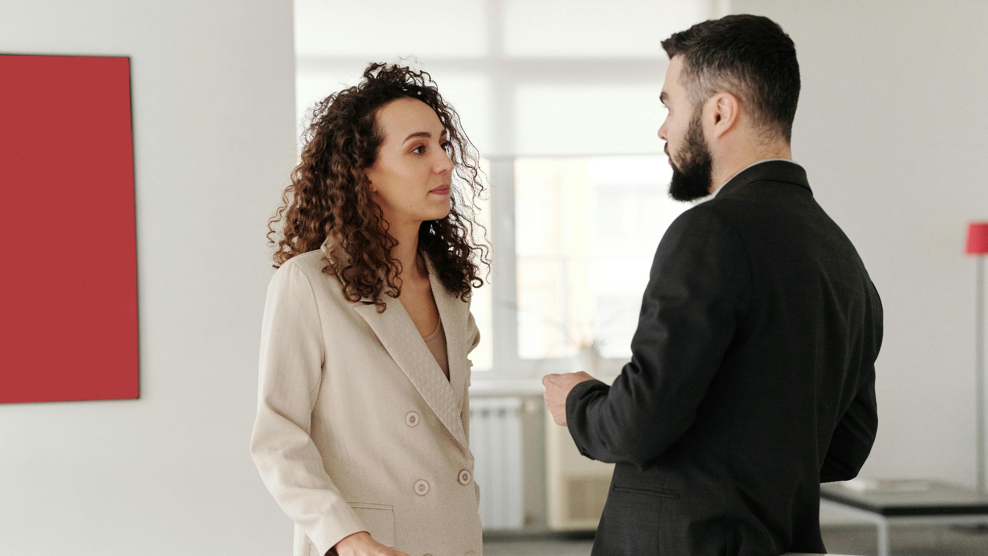 Two professionals engaged in a discussion in a bright, modern office setting.
