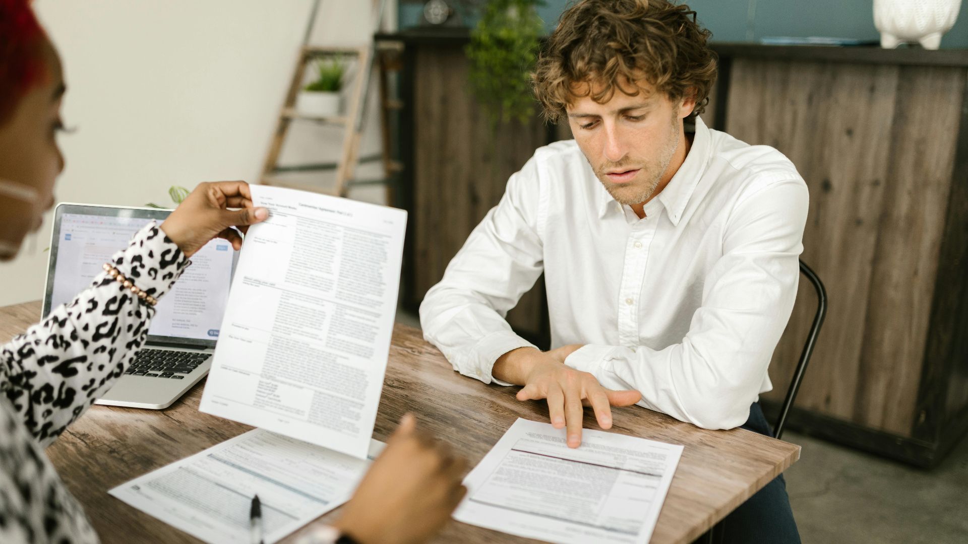 Two professionals reviewing documents in an office setting, focused on analytical tasks.