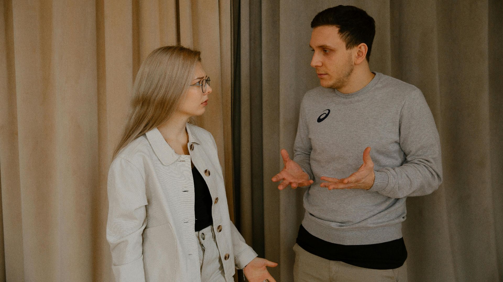 A young couple passionately discussing indoors, capturing intense emotions and gestures.