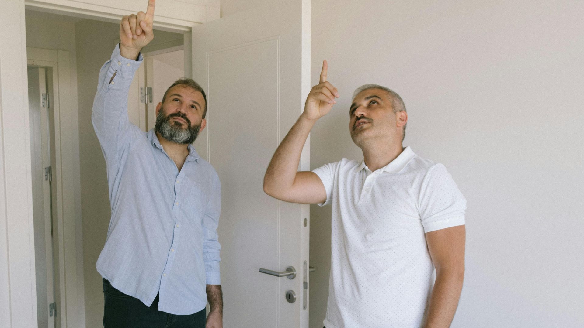 Two adult men pointing and examining interior details in a modern İstanbul apartment.