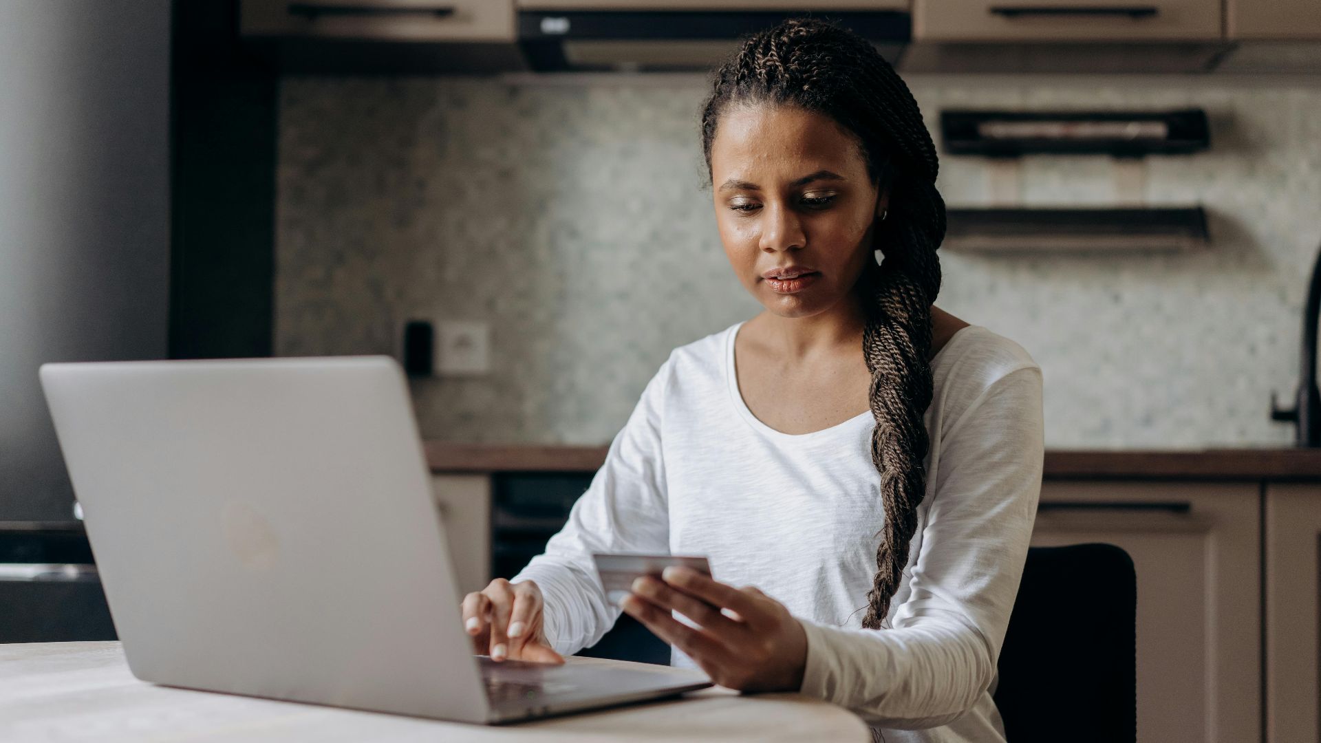 African American woman using laptop and credit card for online shopping at home.