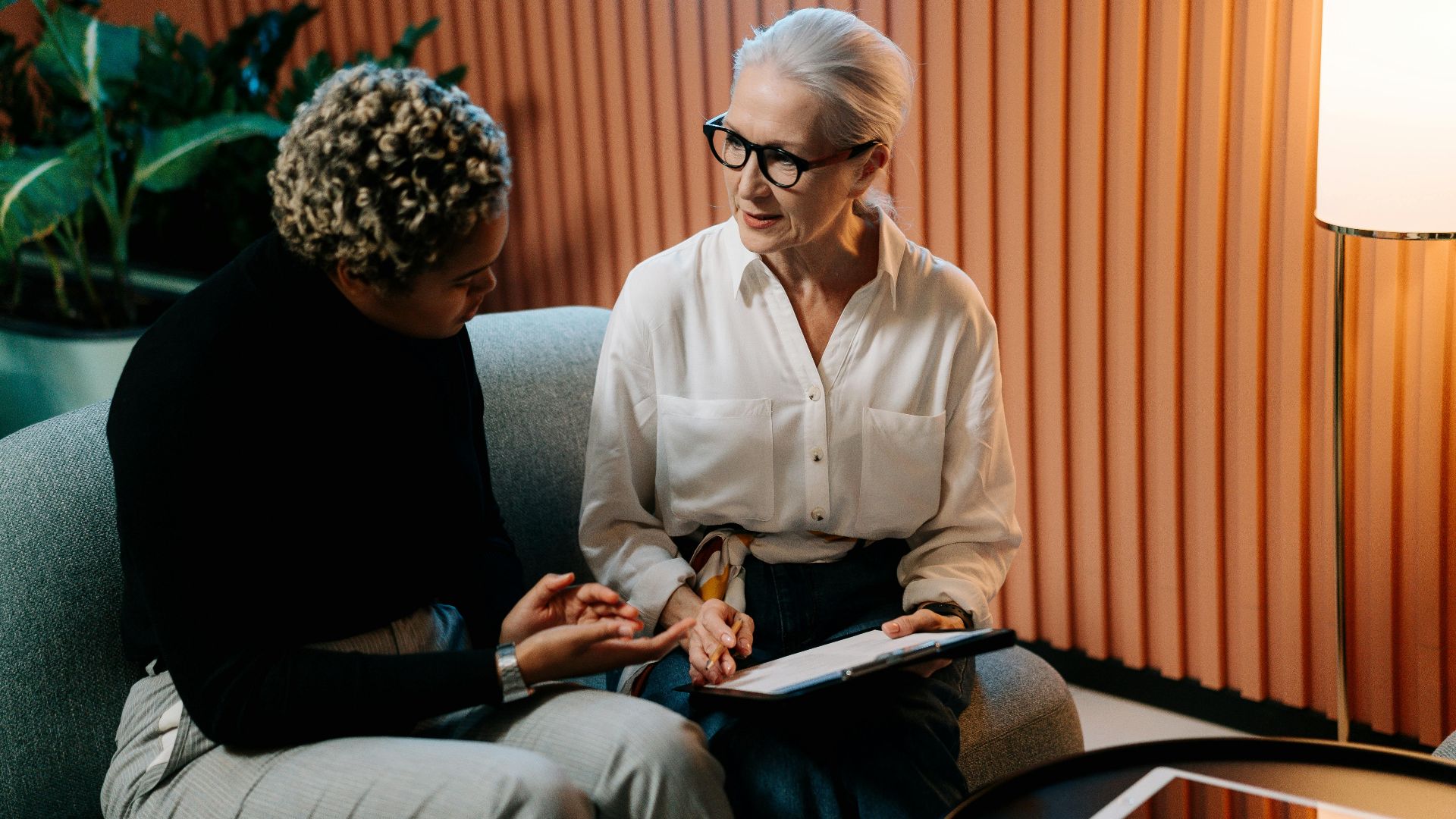 Two professional women engaged in a business discussion indoors with documents.