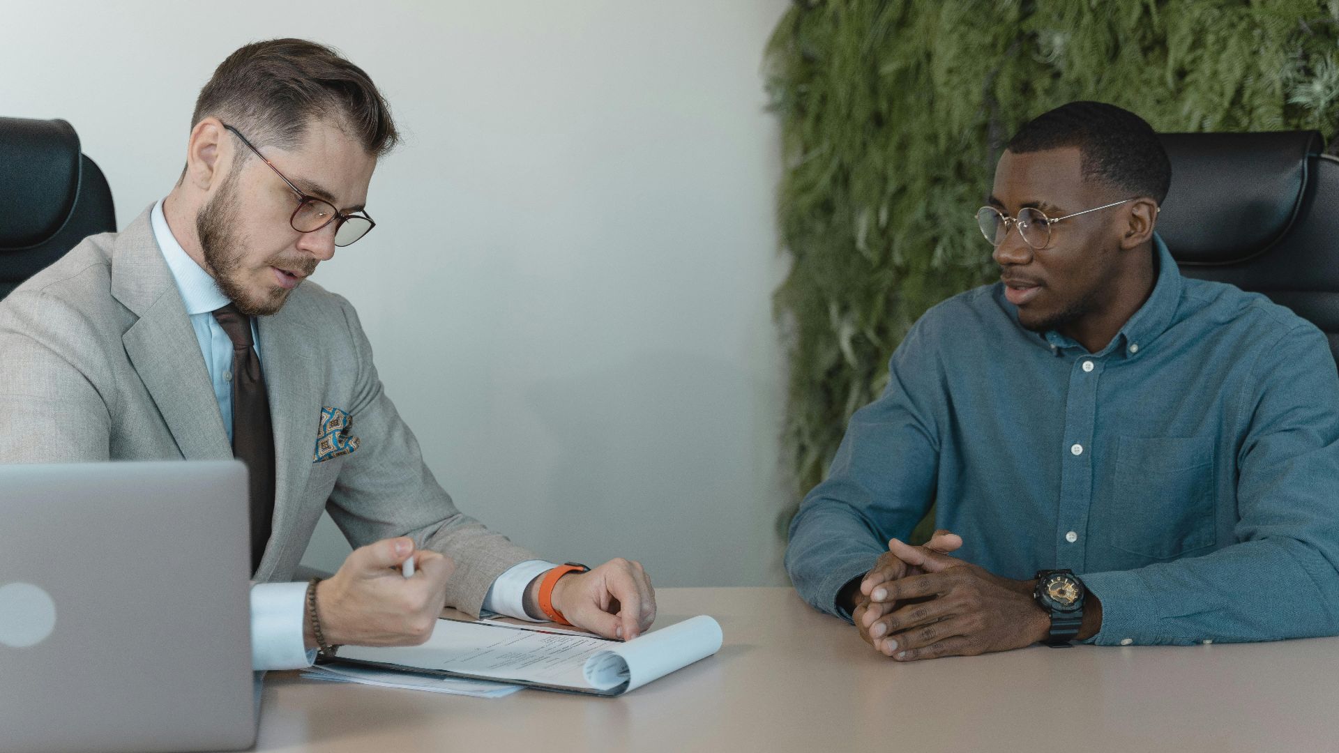 A professional job interview between two men in a modern office environment.
