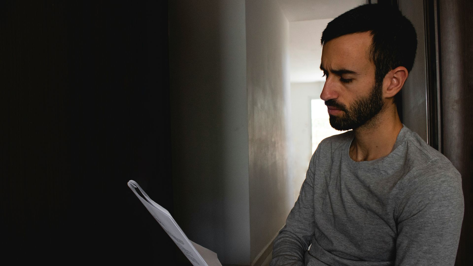 man in gray crew neck shirt holding white printer paper