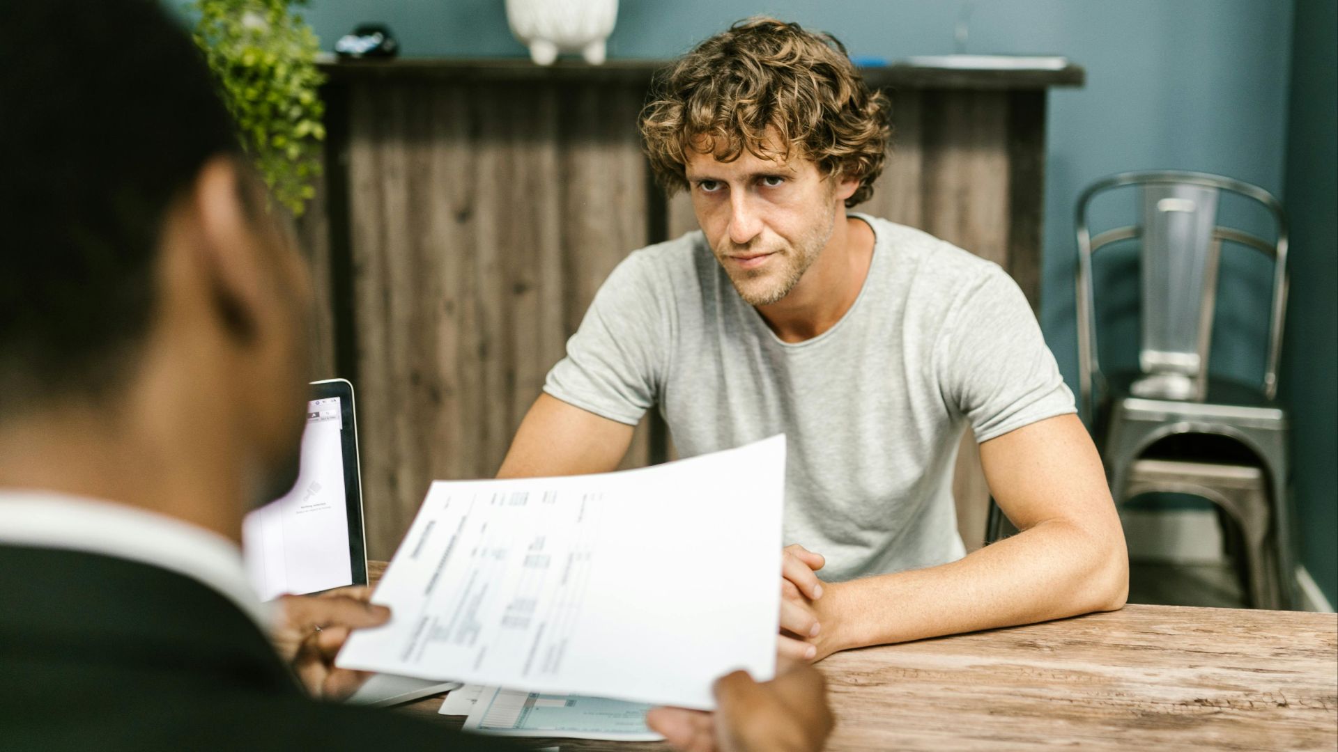 Two men in discussion over documents during a business meeting in a contemporary office setting.