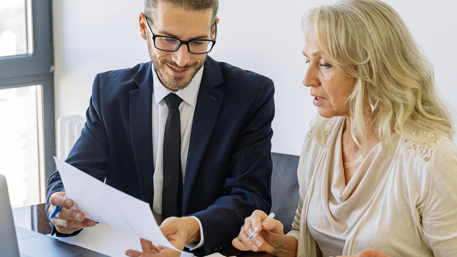 Two business professionals reviewing financial documents and graphs during a meeting.