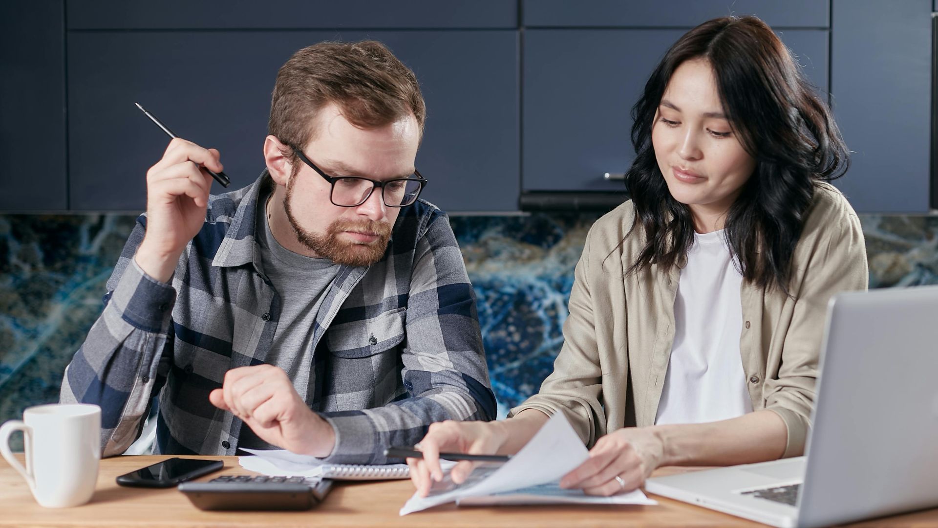 A couple is reviewing and calculating their household bills together at home.