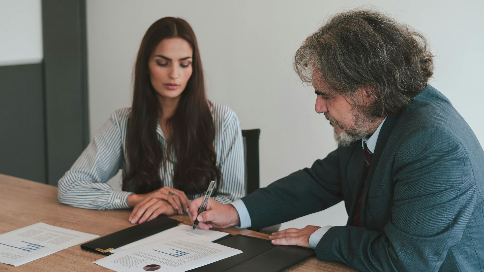 Professional business meeting with two colleagues reviewing documents at an office desk.