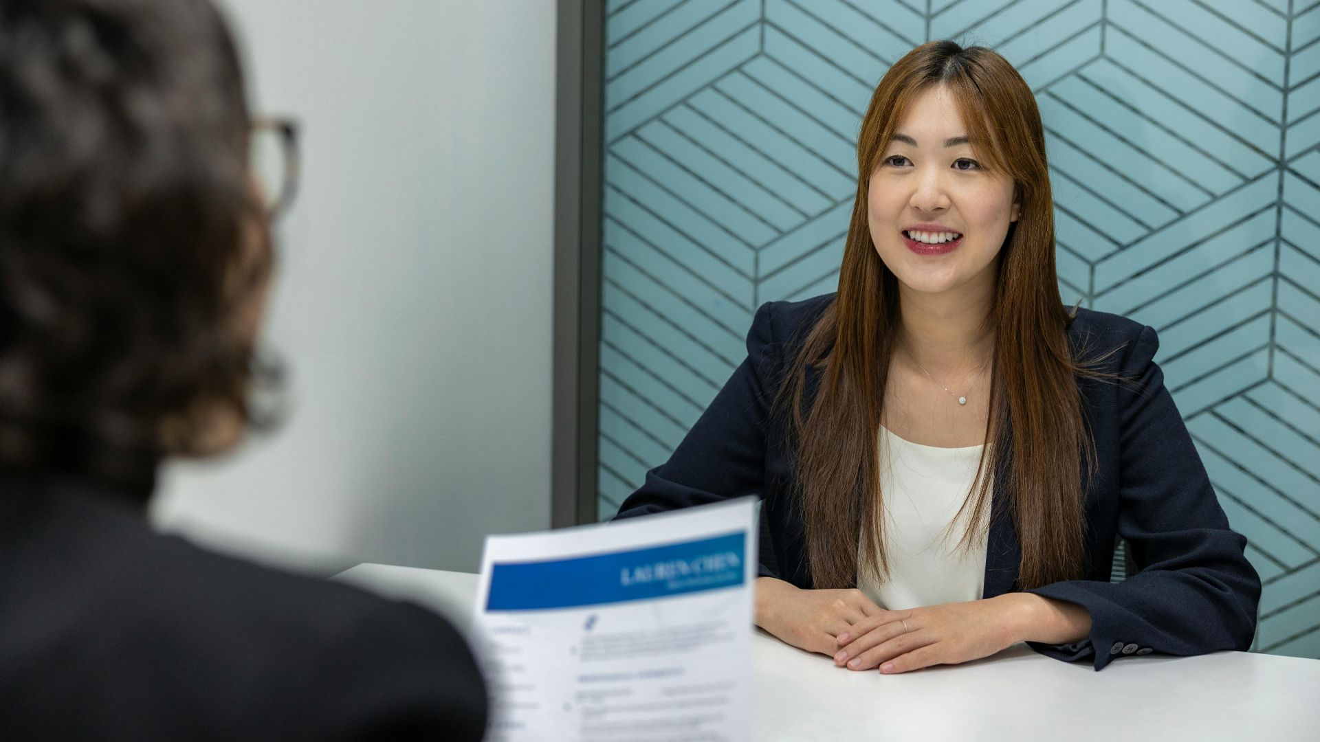 Young woman in a business meeting with an interviewer, showcasing confidence and professionalism.