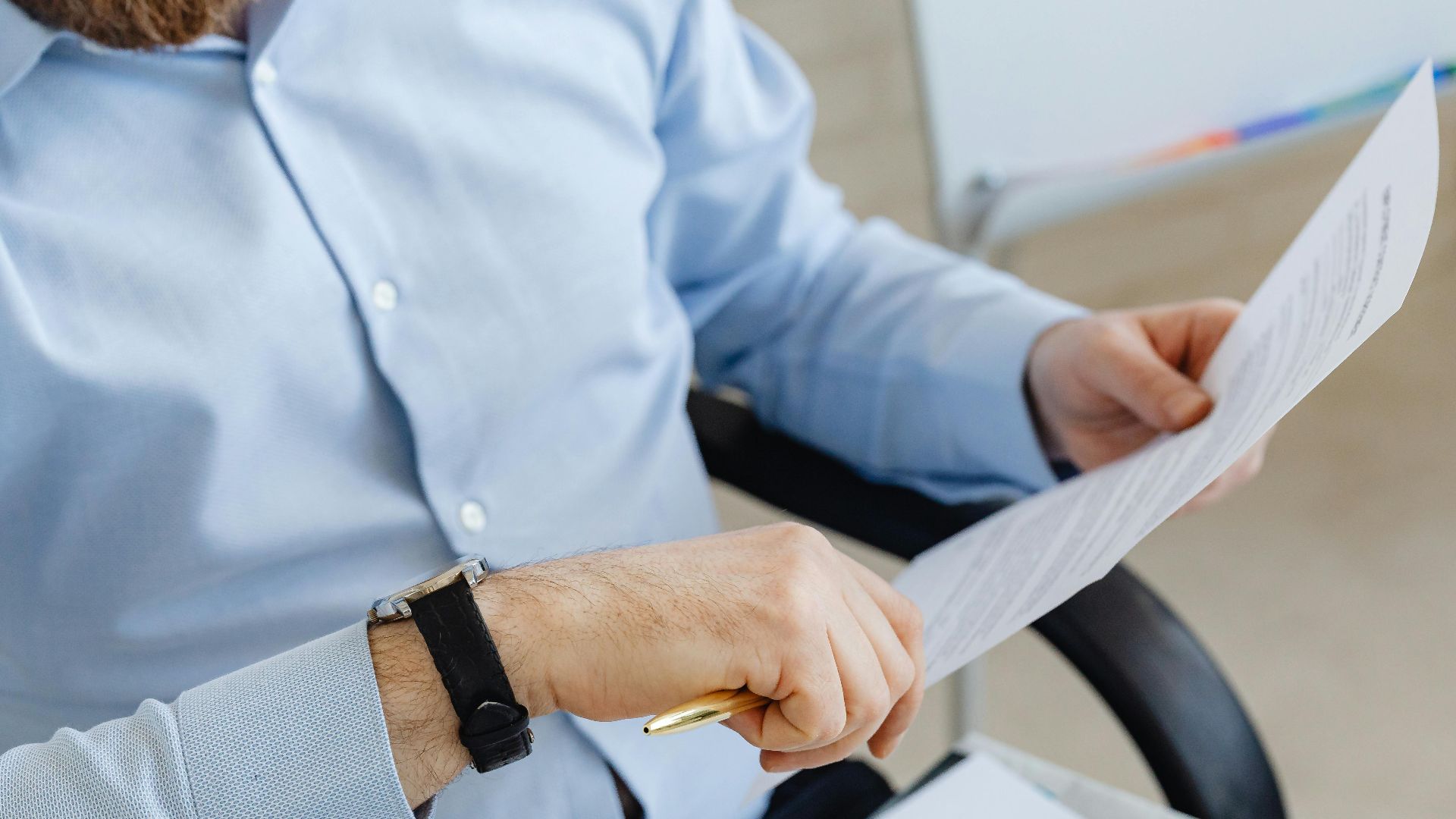 Businessman reviewing papers in office setting, highlighting analysis and attention to detail.