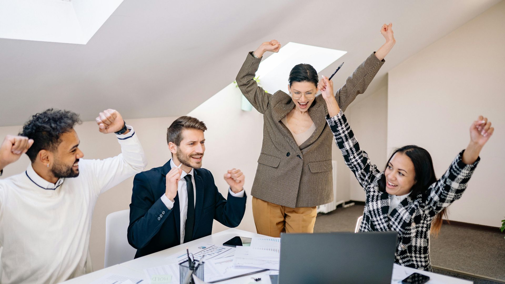 Diverse group of professionals celebrate a team success in a contemporary office setting.