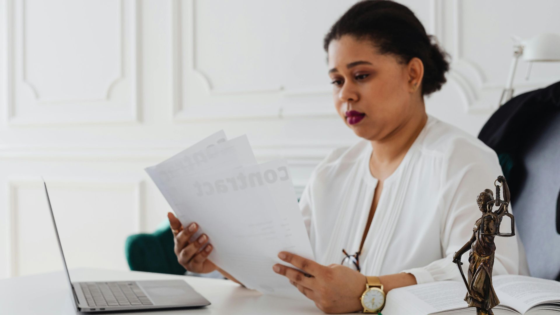 Black woman lawyer reading legal papers at her desk in a modern office.