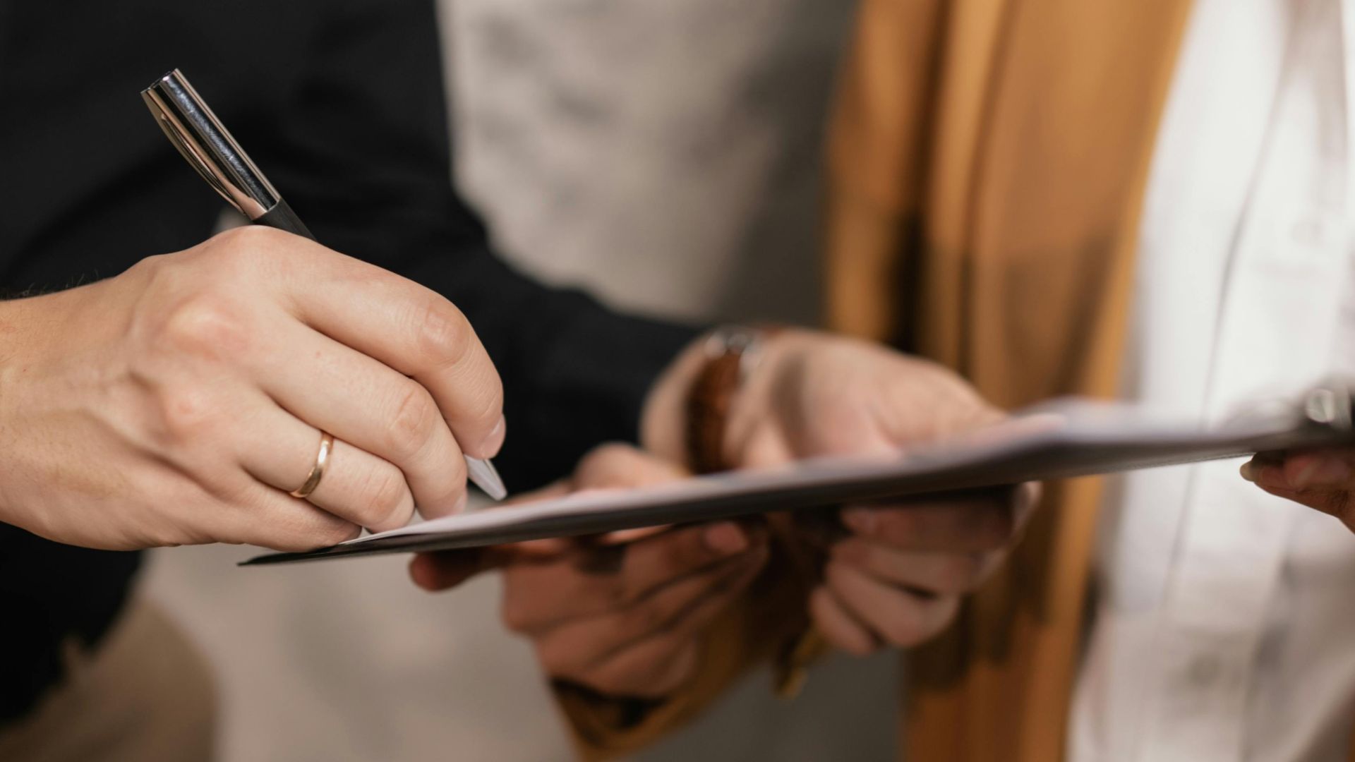 Close-up of two professionals signing a business document, emphasizing collaboration and negotiation.