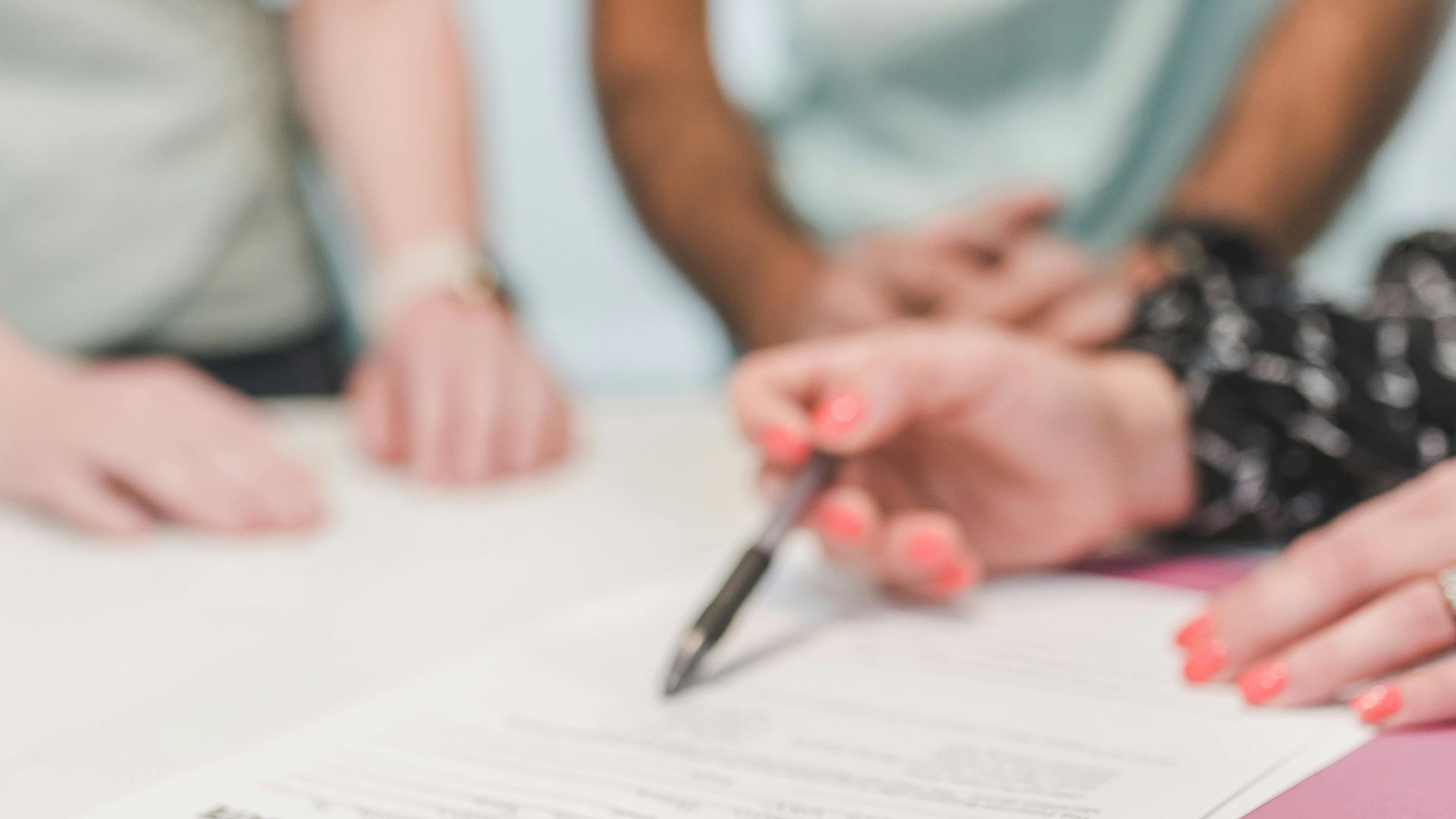 Close-up of people reviewing and signing an offer to purchase real estate document.