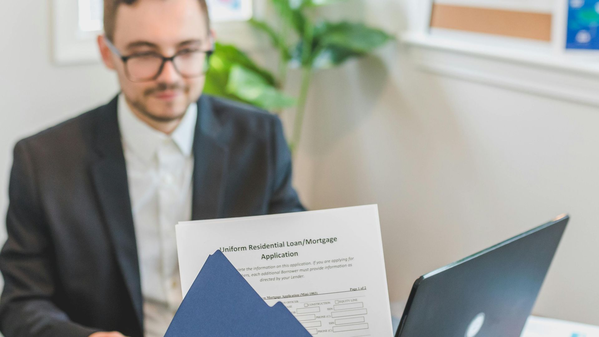 Mortgage broker and client discussing loan application with documents on table.