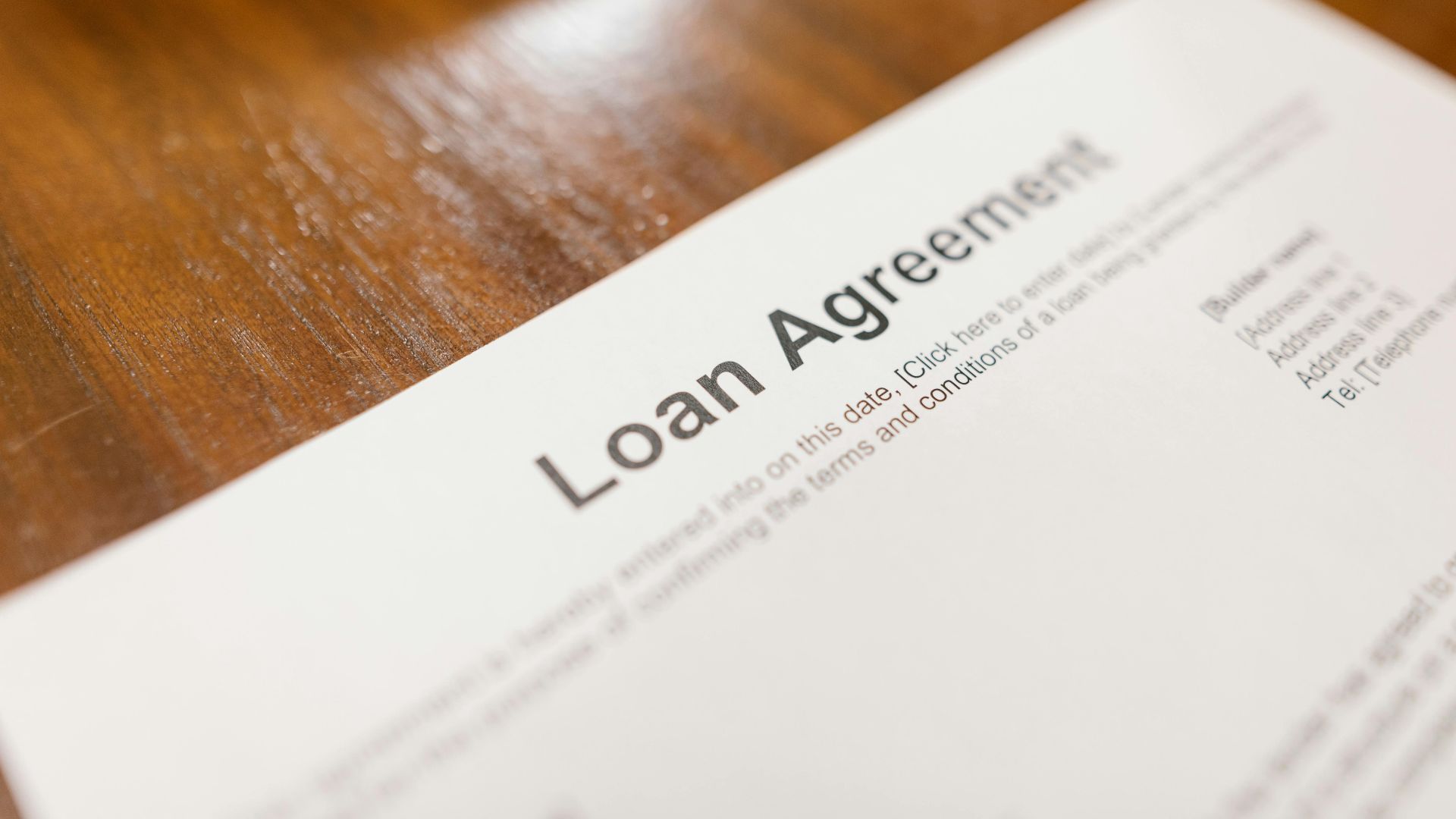 Detailed loan agreement document close-up on a wooden table representing legal and financial concepts.