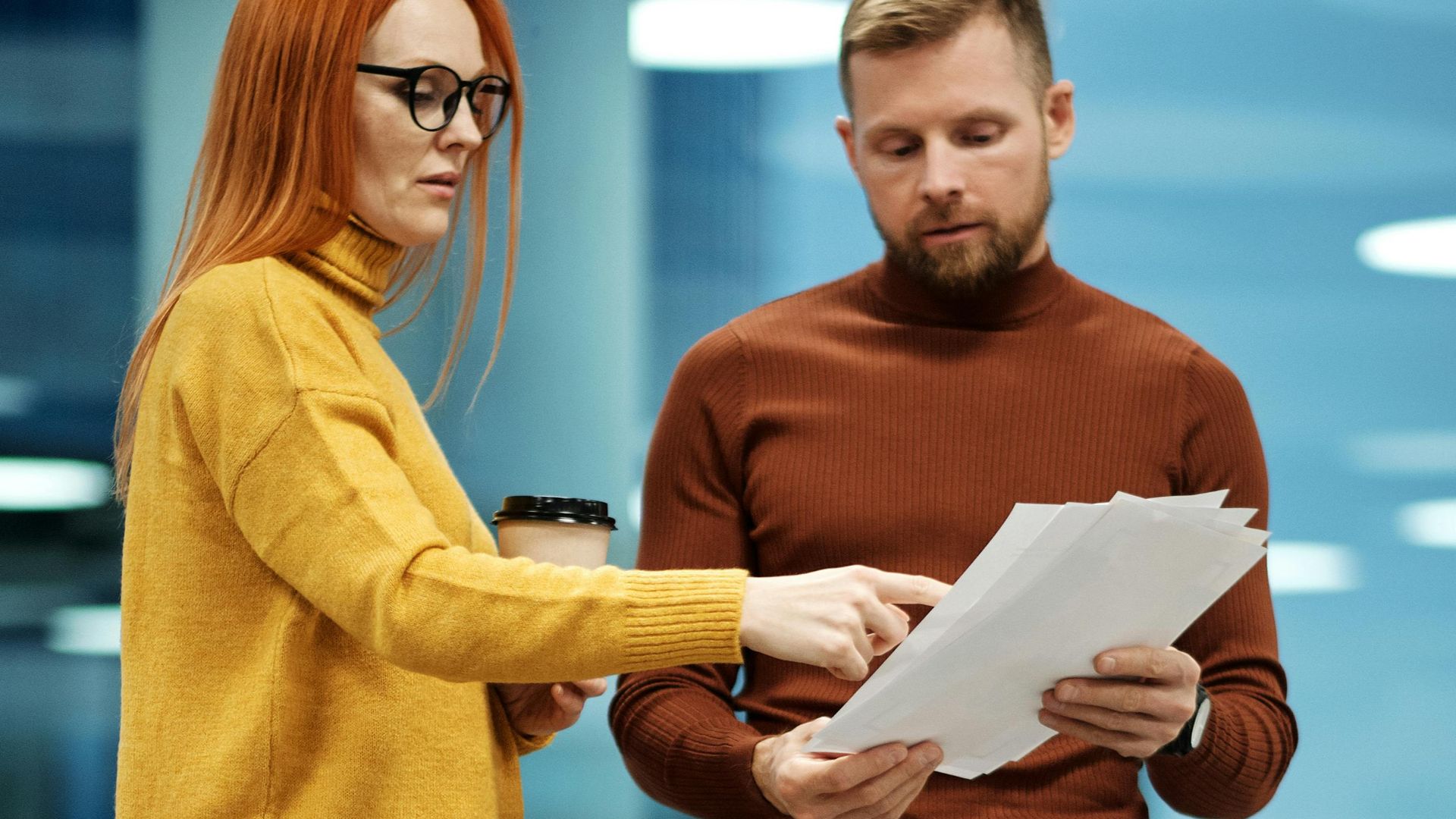 Two professionals collaborating and reviewing documents in a sleek office setting.